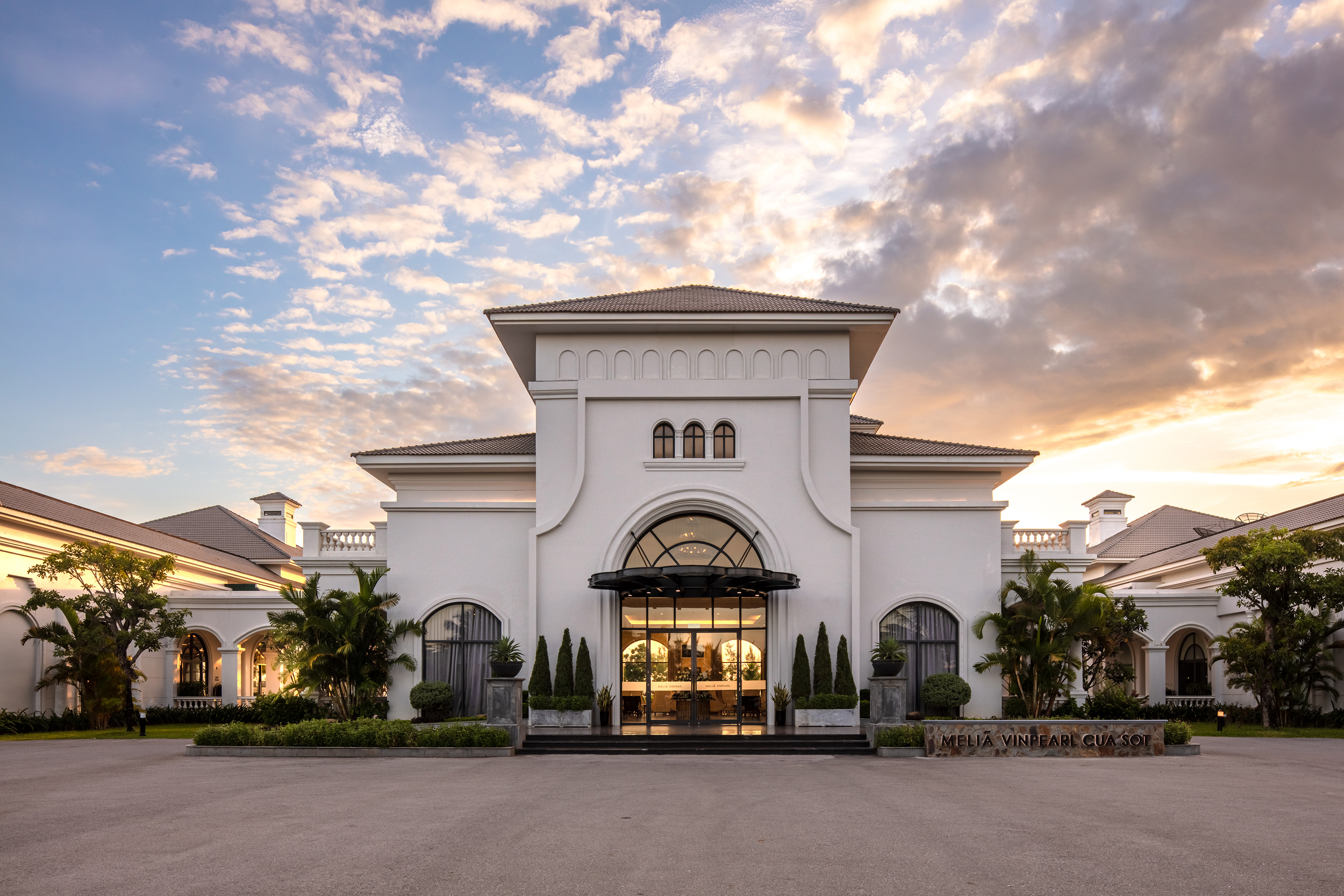 a building with a lot of trees and a cloudy sky