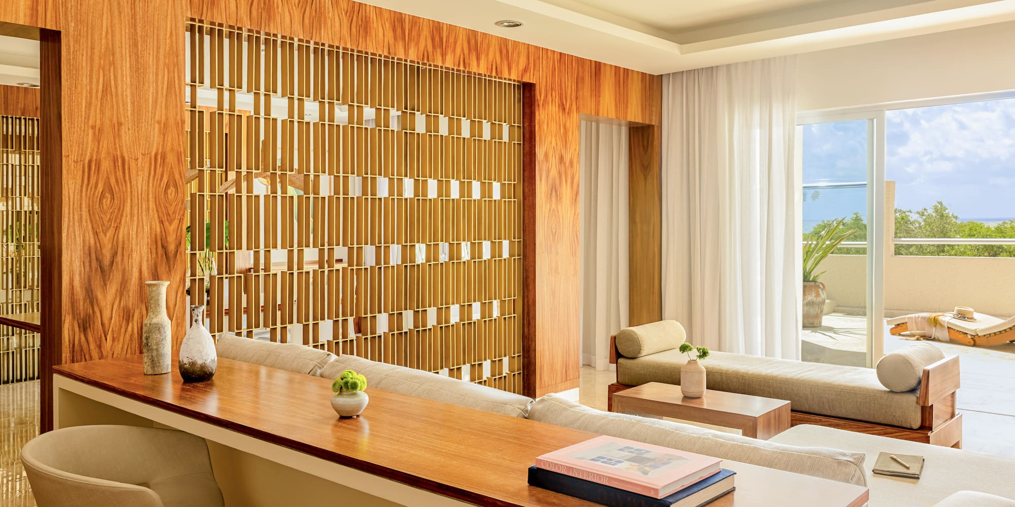 Modern living room with wood panels, decorative divider, lounge sofas, and patio view.