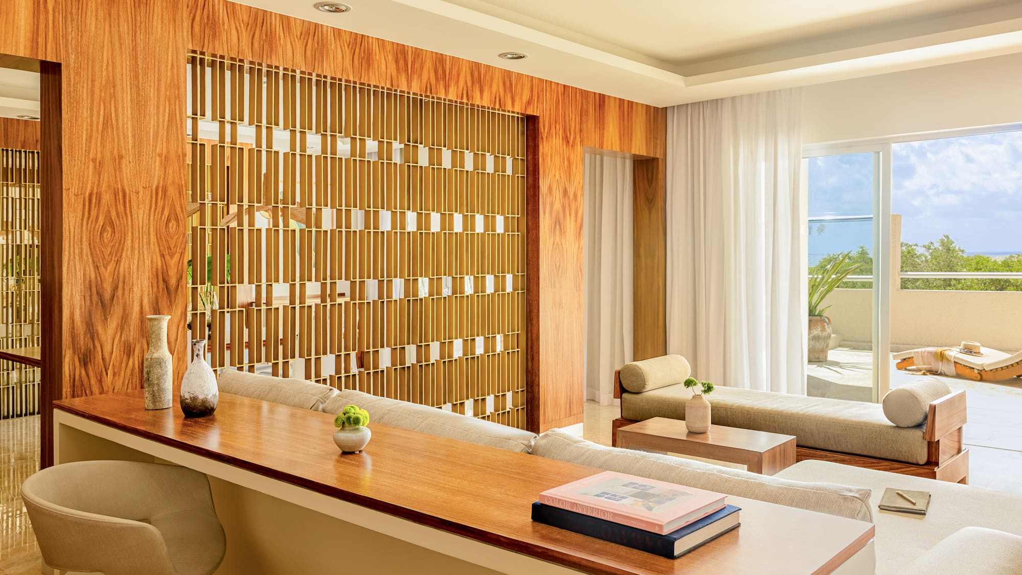 Modern living room with wood panels, decorative divider, lounge sofas, and patio view.