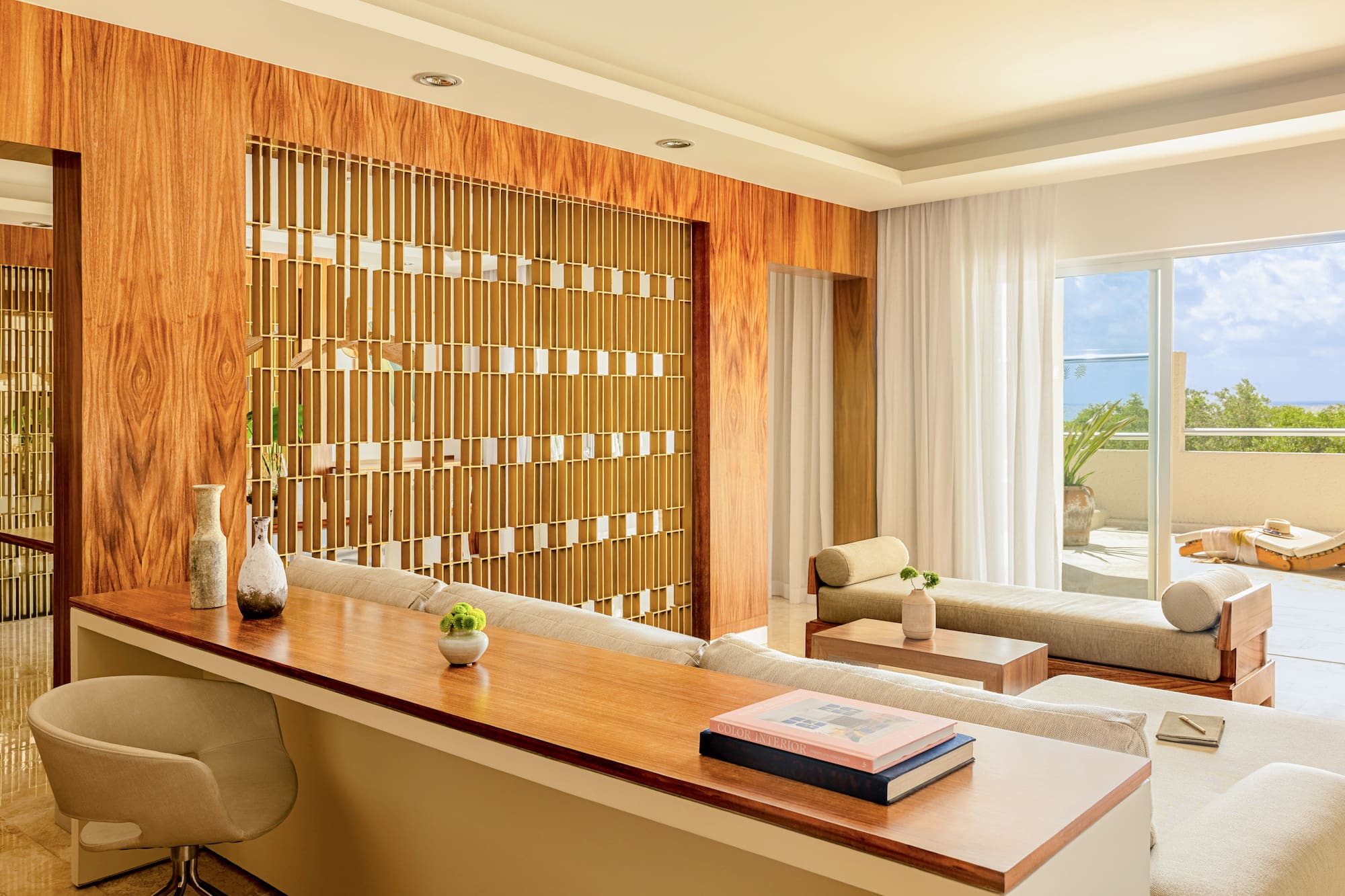 Modern living room with wood panels, decorative divider, lounge sofas, and patio view.