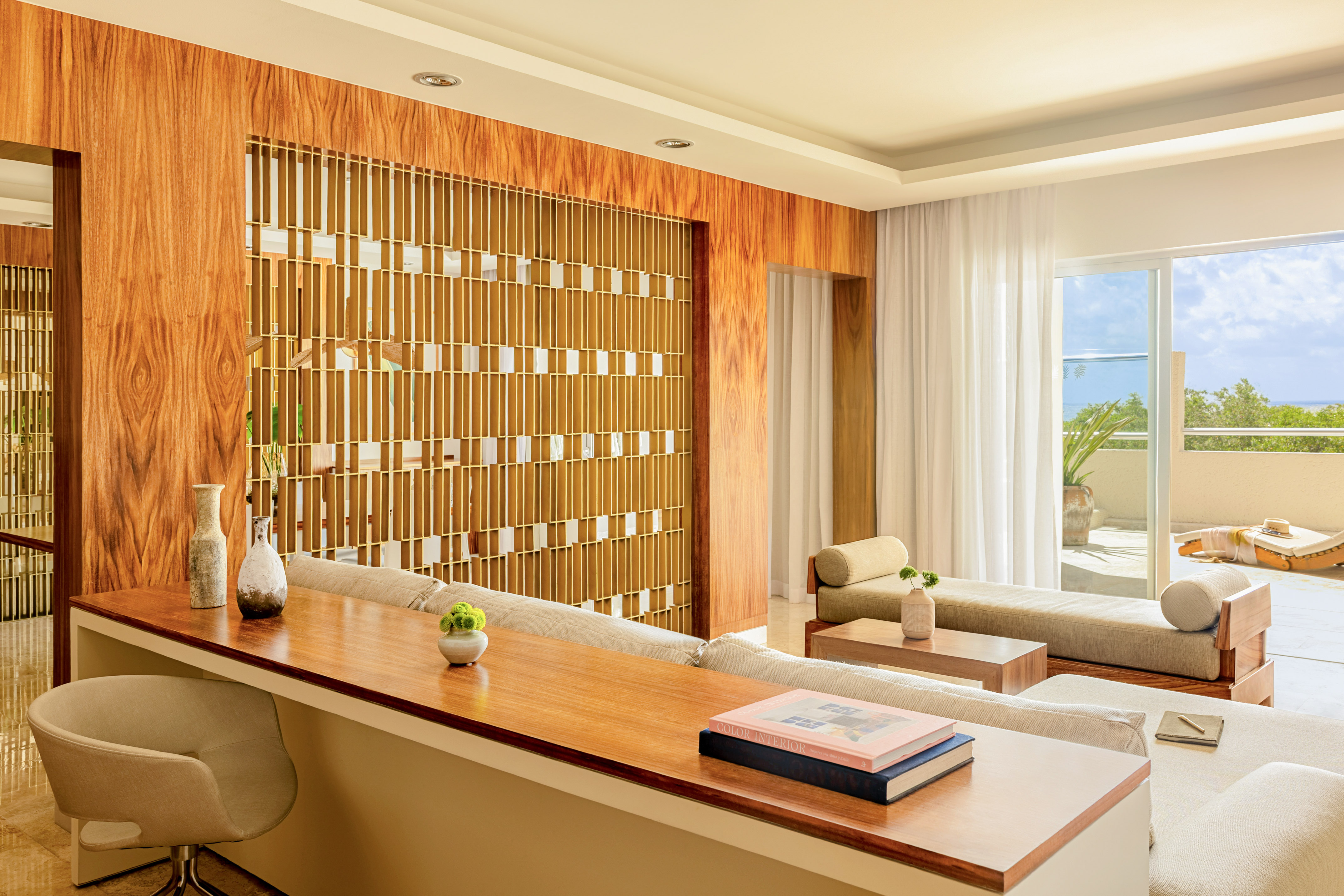 Modern living room with wood panels, decorative divider, lounge sofas, and patio view.