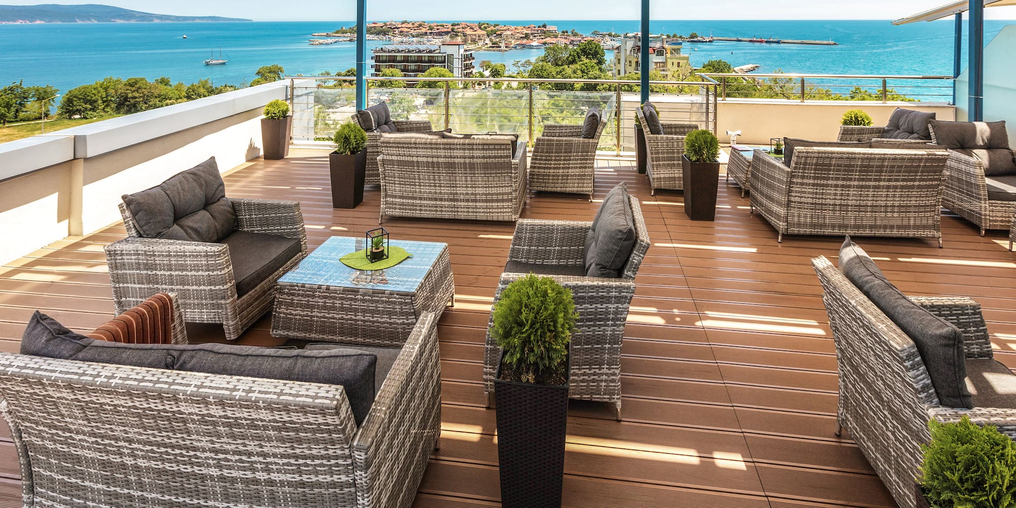 a patio area with chairs and tables on a deck overlooking the ocean