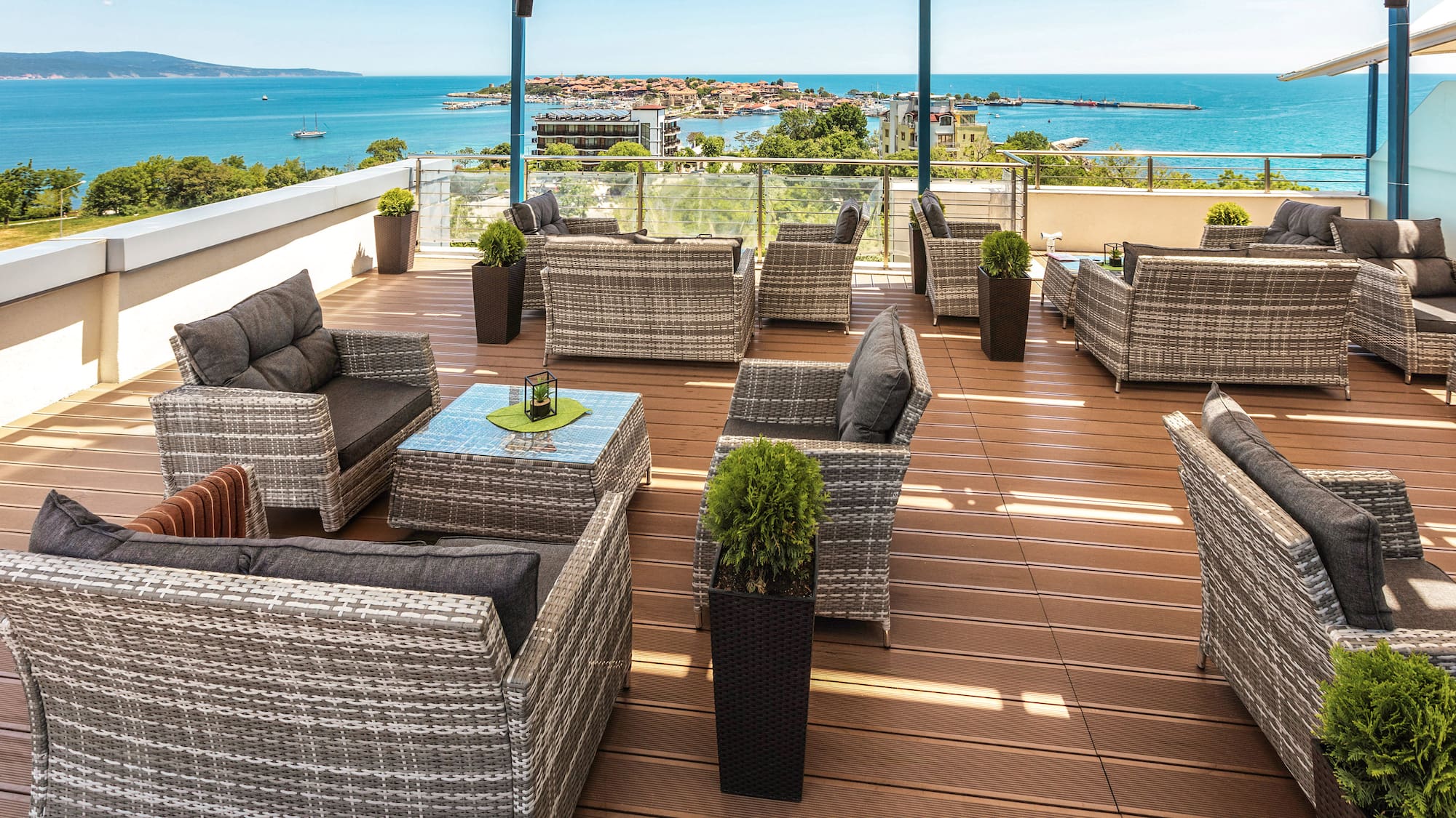 a patio area with chairs and tables on a deck overlooking the ocean