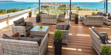 a patio area with chairs and tables on a deck overlooking the ocean