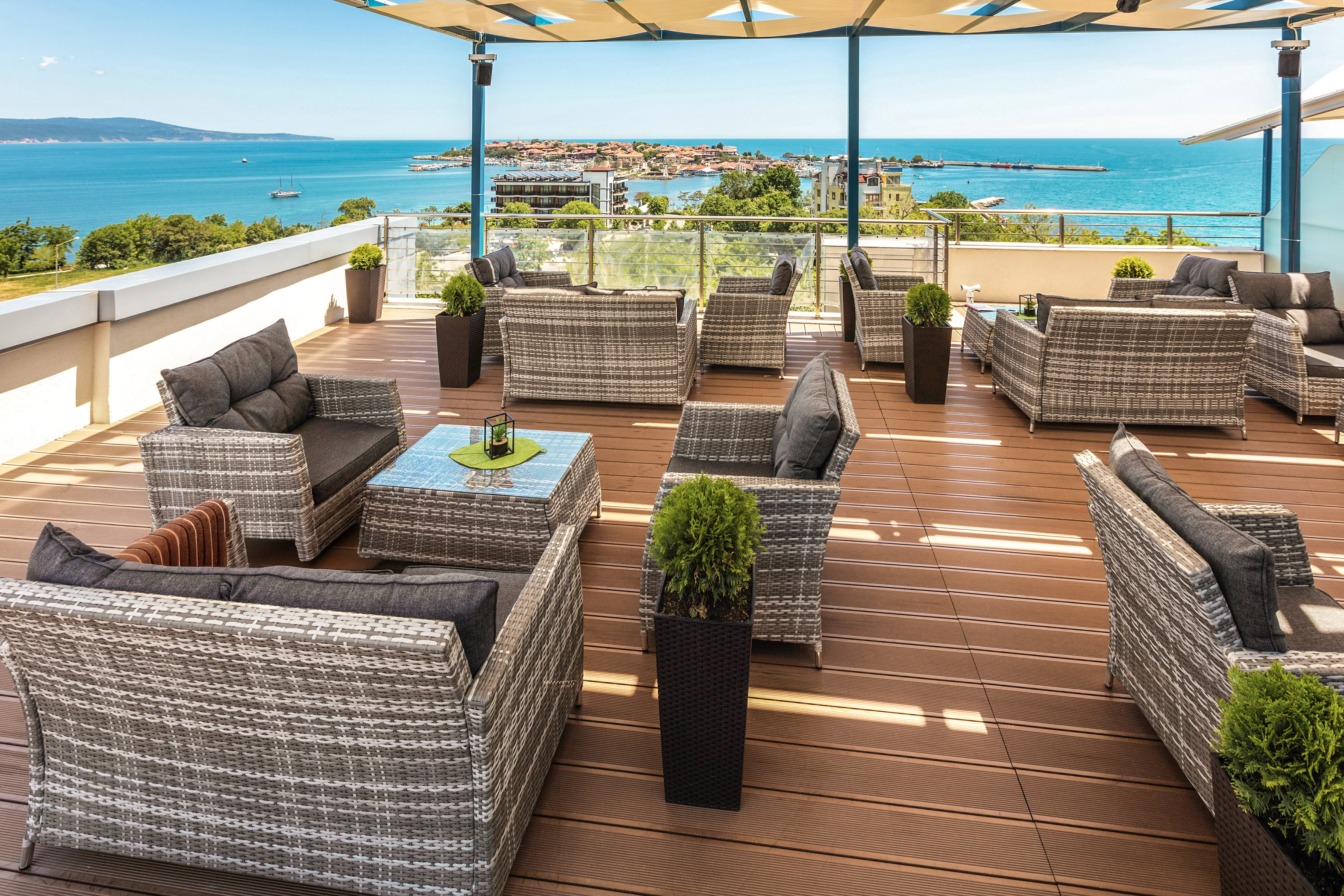a patio area with chairs and tables on a deck overlooking the ocean