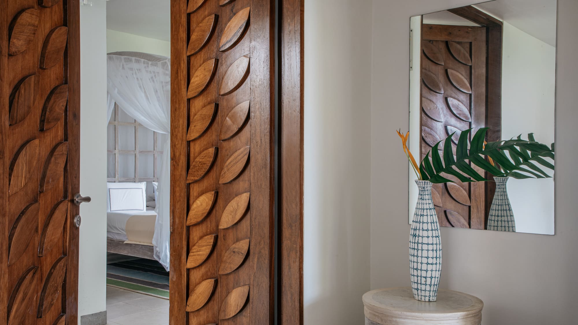 a room with a door and a vase of flowers