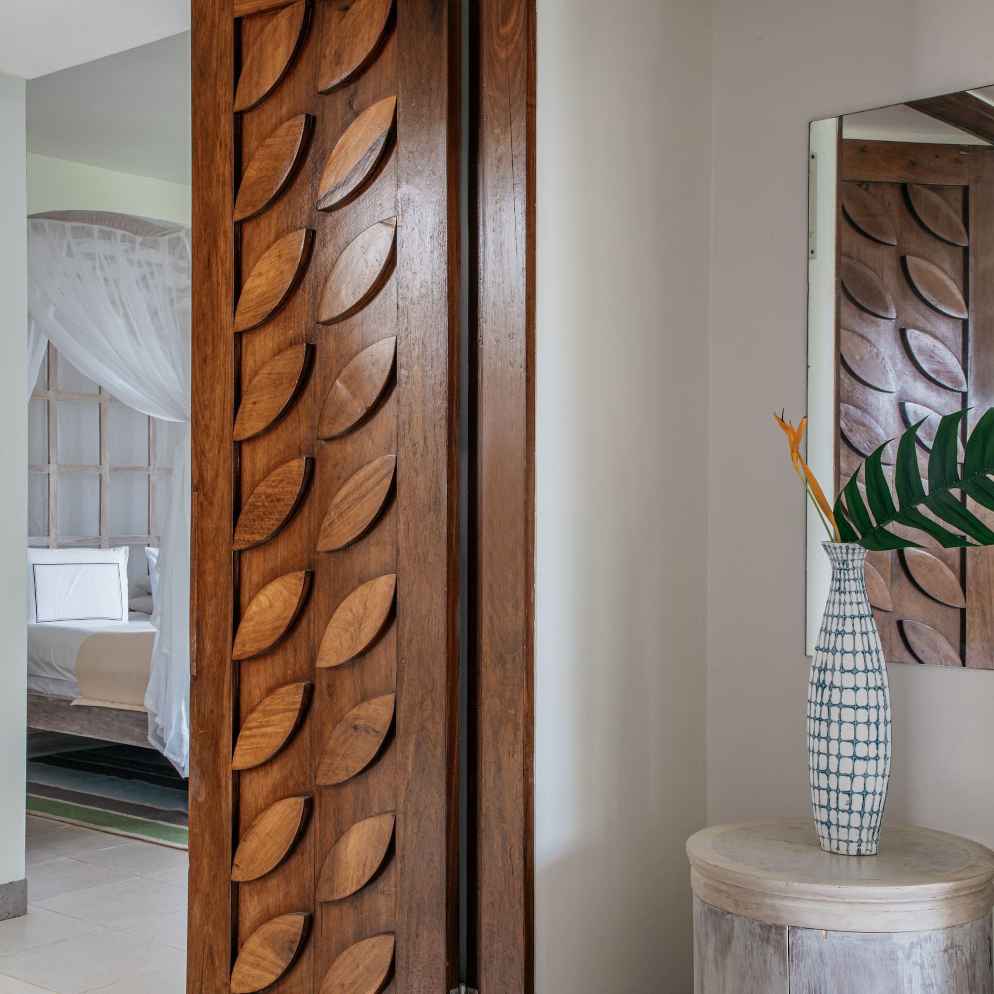 a room with a door and a vase of flowers