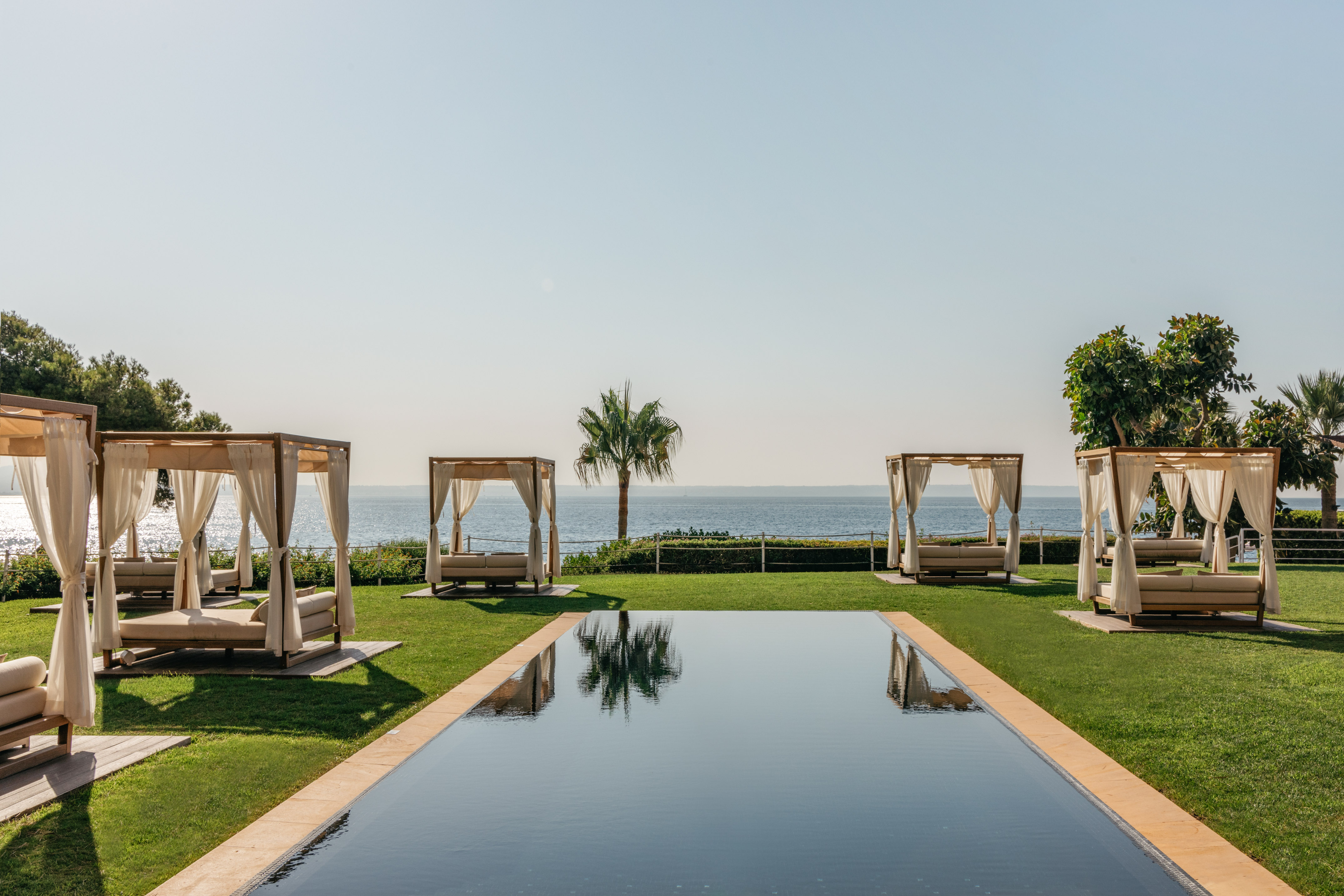 a pool with beds and a body of water in the background.