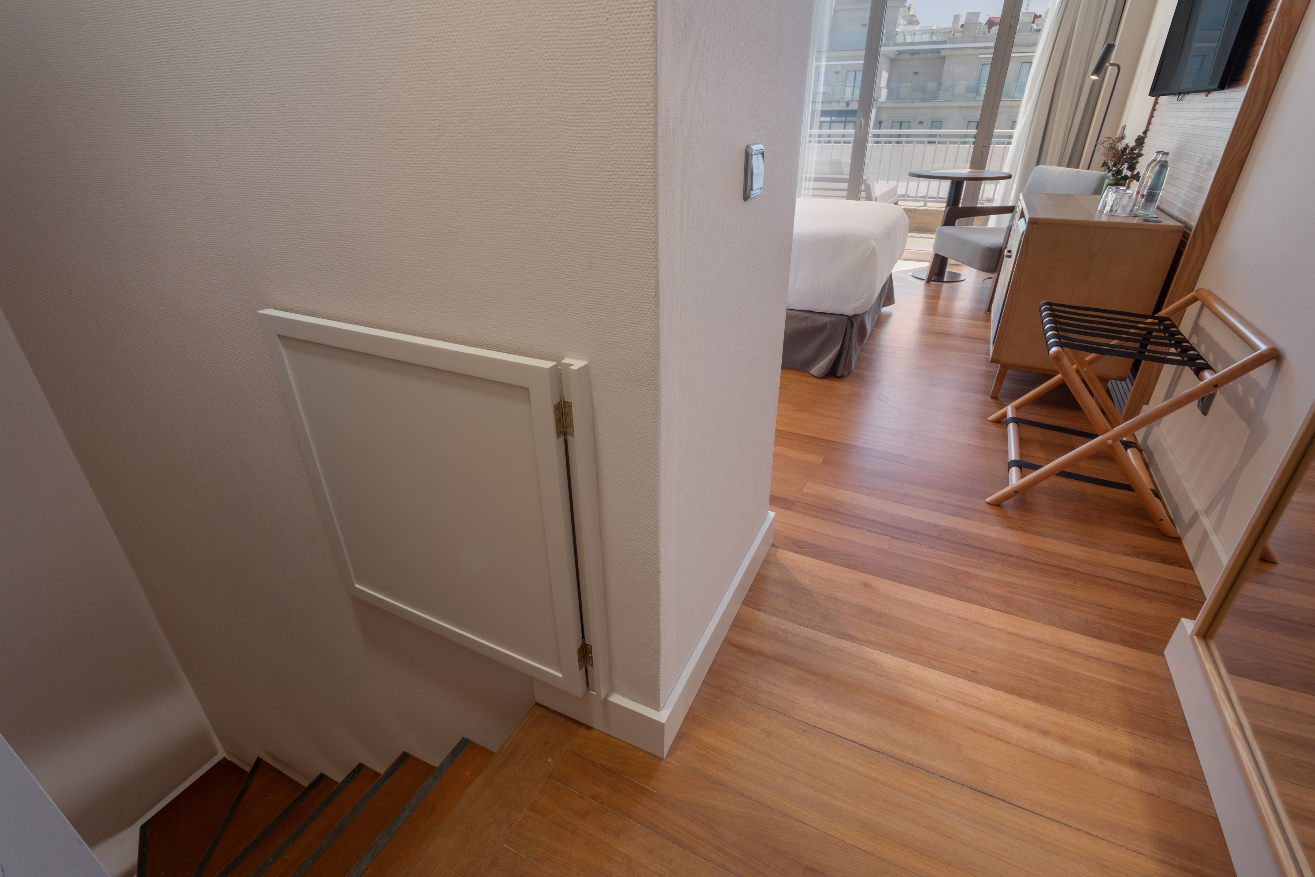 Split-level hotel suite with wooden stairs, bedroom, hardwood floor, balcony.