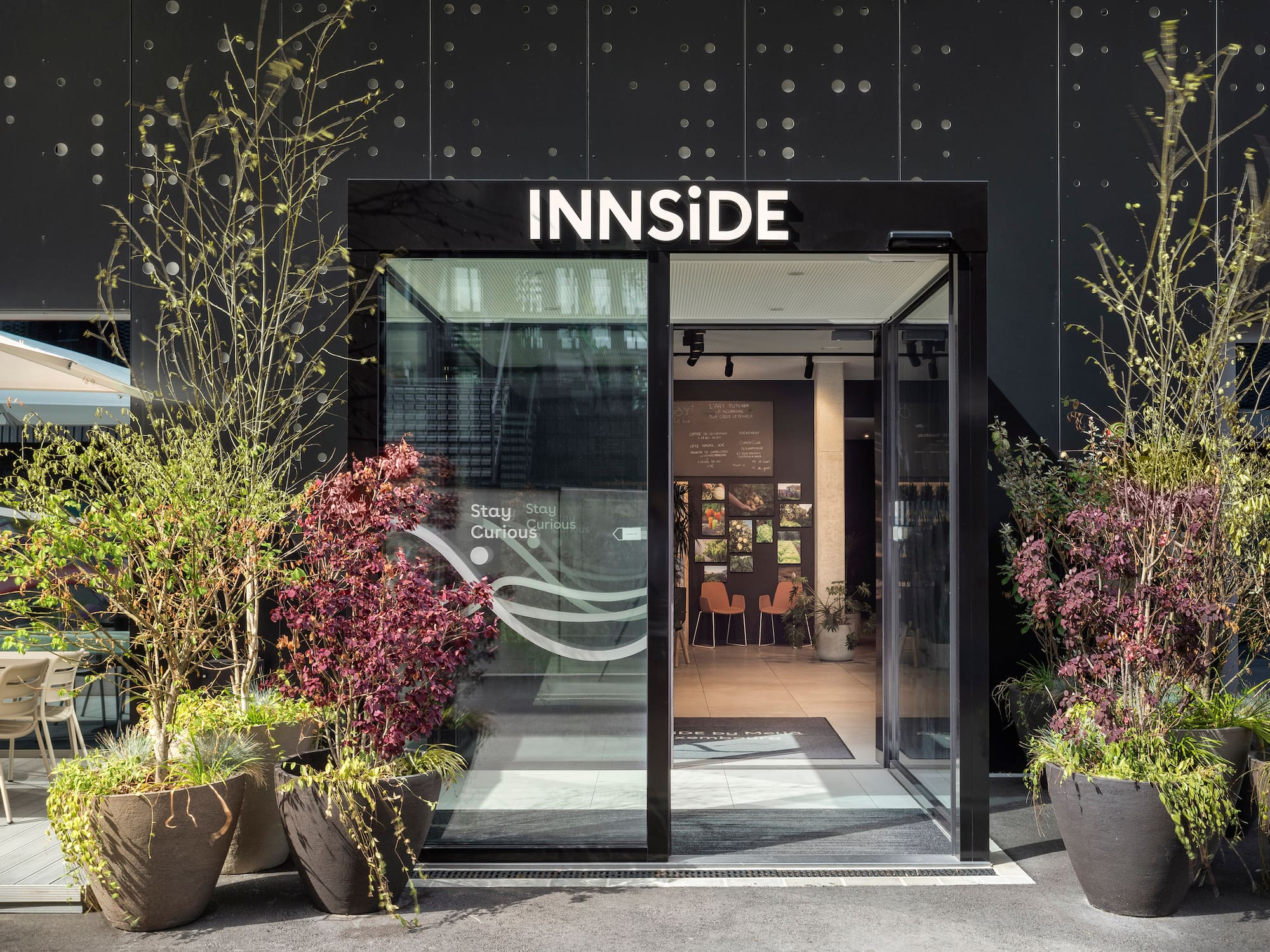 Modern Innside hotel entrance with glass doors, potted plants, and outdoor patio.