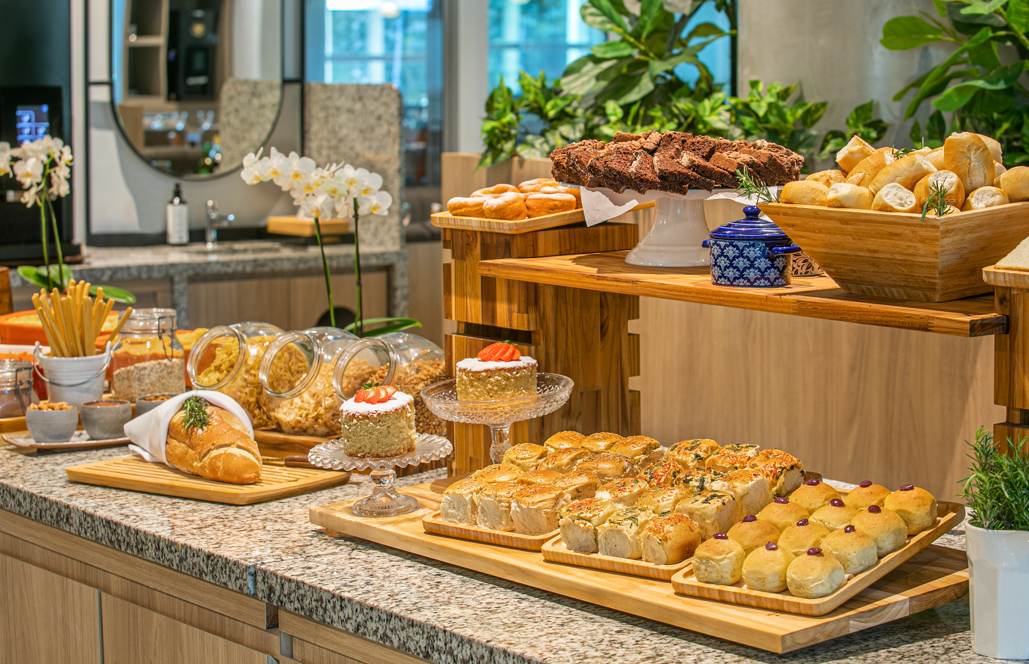 Breakfast buffet with pastries, breads, cakes, and cereals on a tiered display.