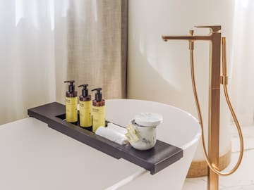 a bathtub with a tray of soap and a container of cream