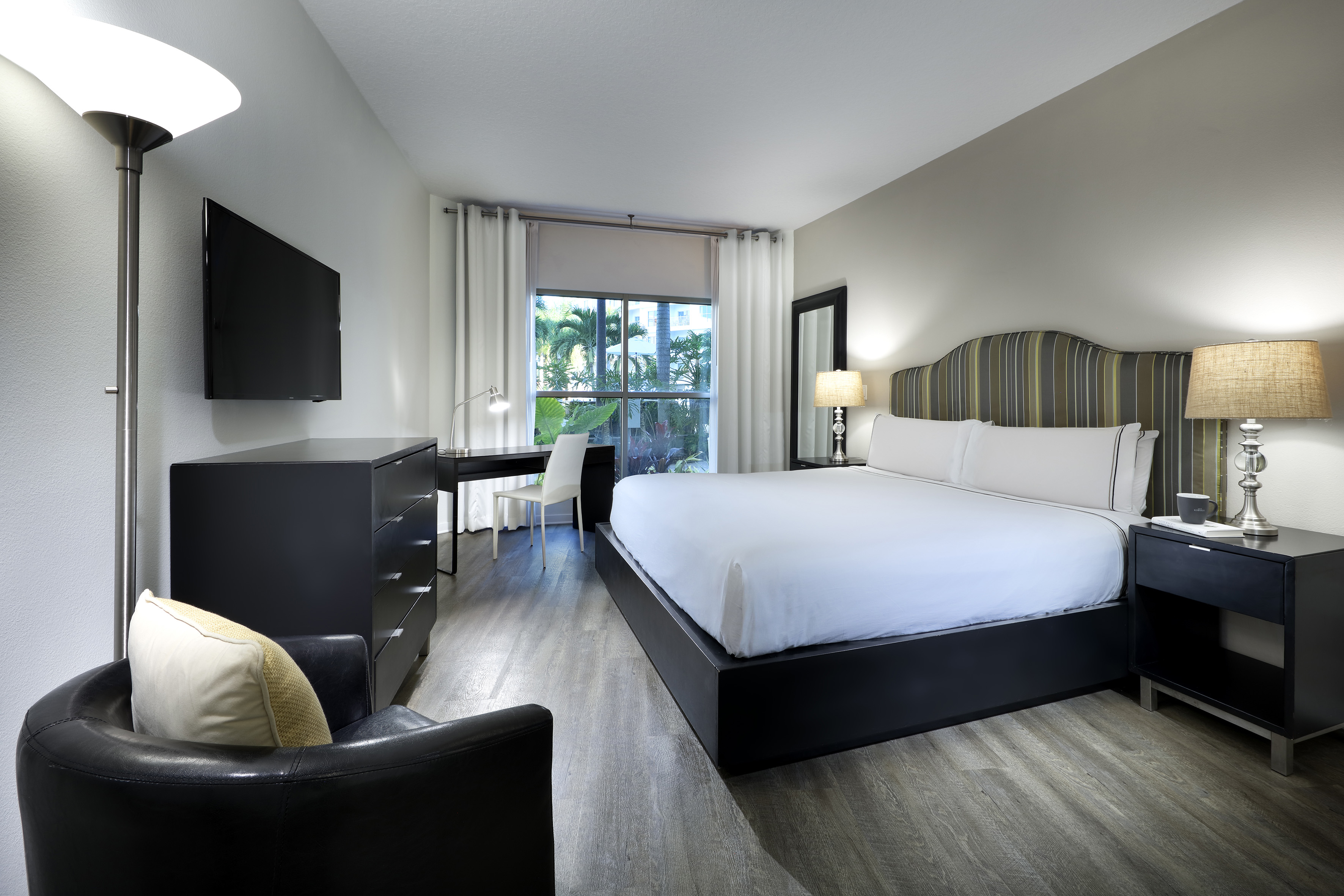 Modern hotel bedroom with king bed, black furniture, tropical view window. - Accessible Room - Meliá Orlando Celebration, Orlando