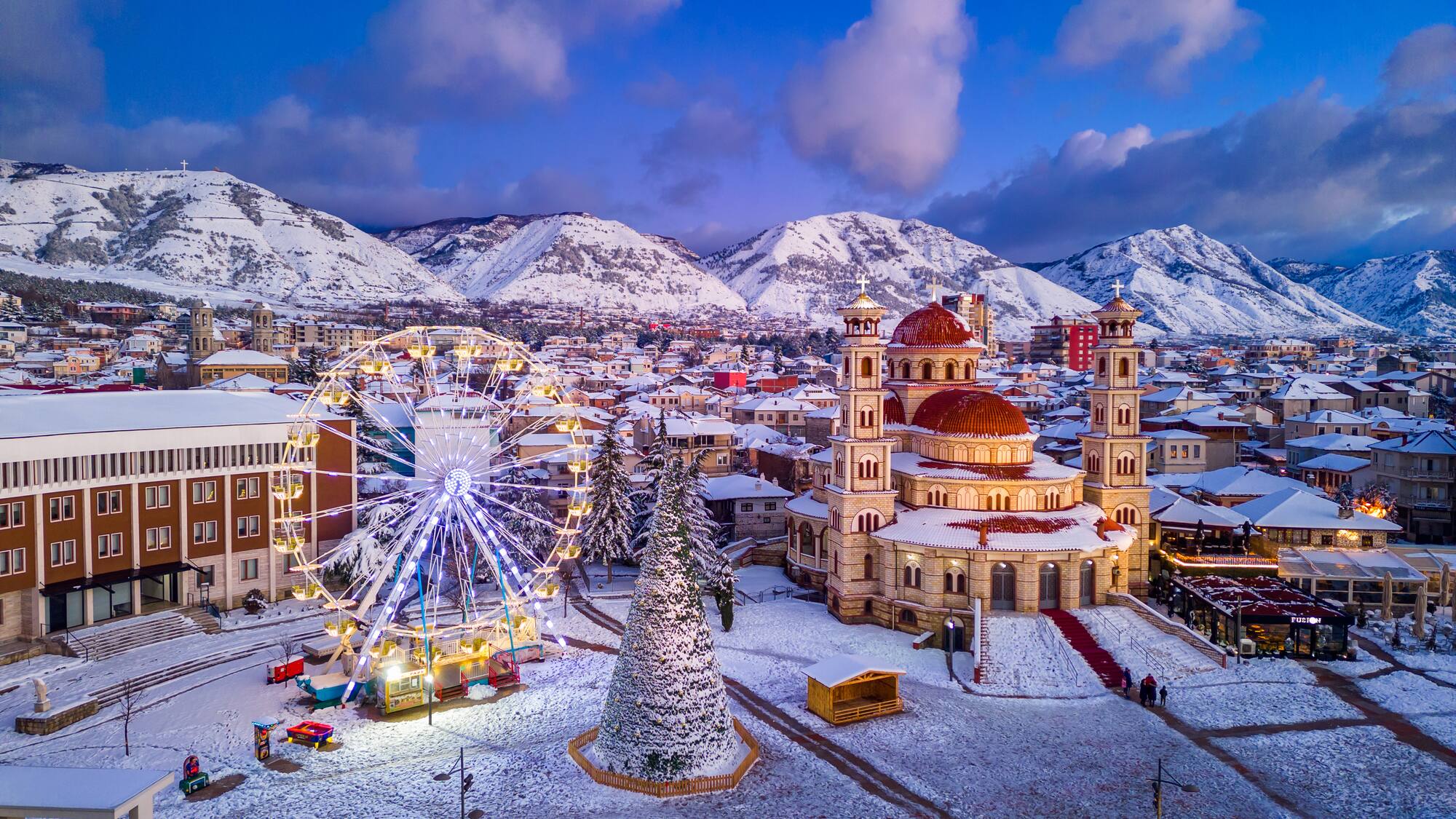 a city with snow covered mountains and trees
