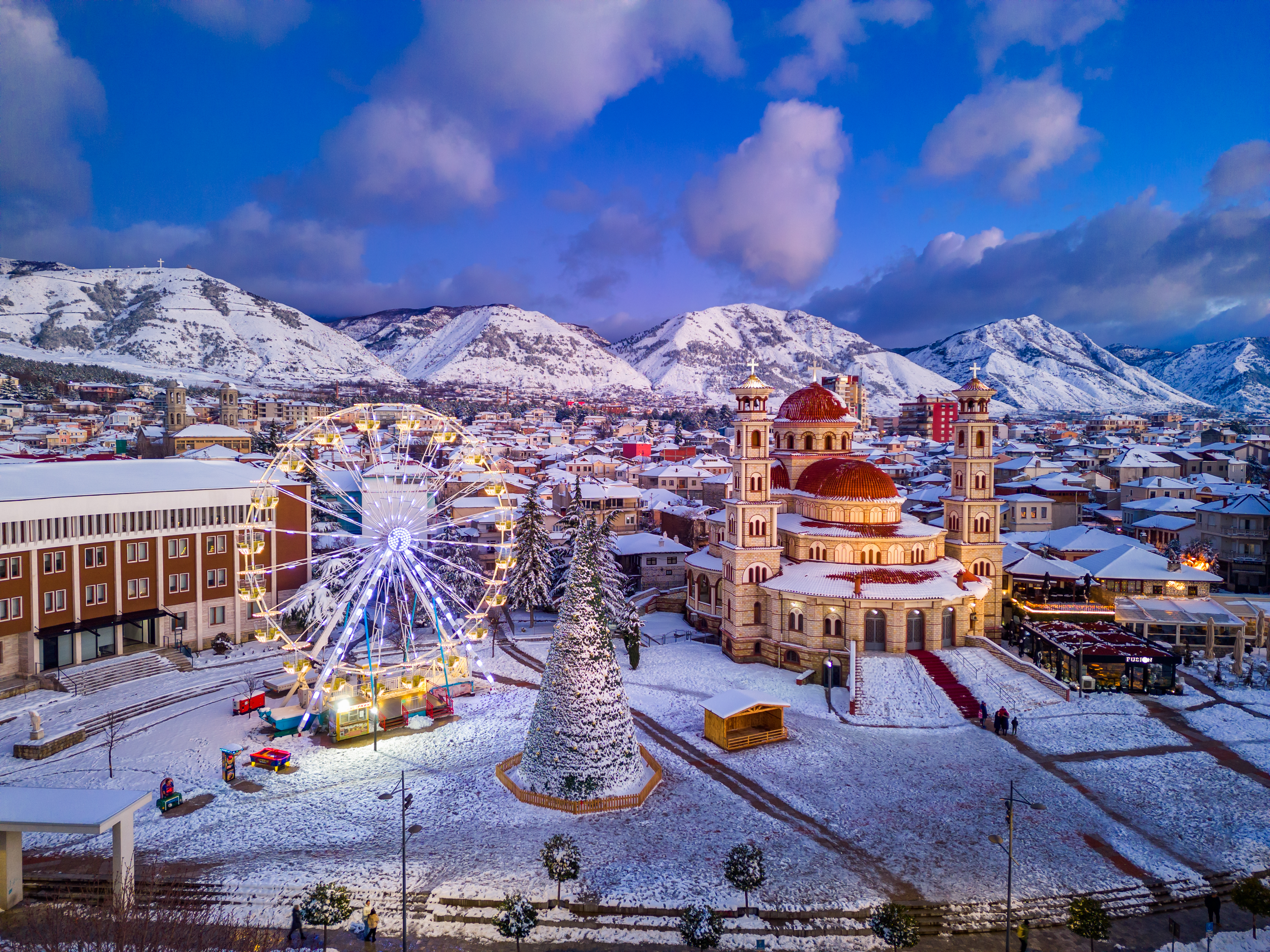 a city with snow covered mountains and trees