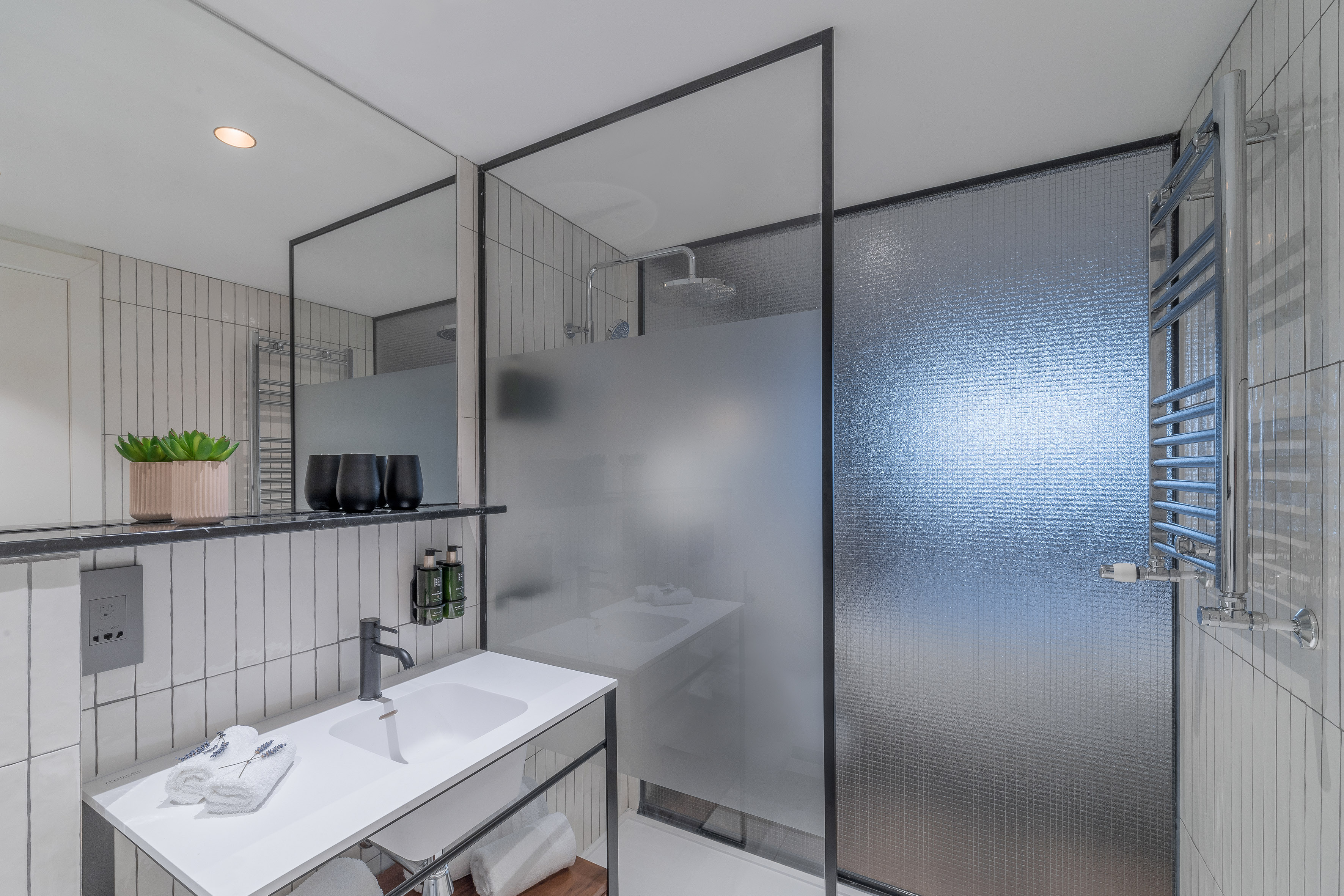 Modern bathroom with white vanity, black faucet, and glass shower.