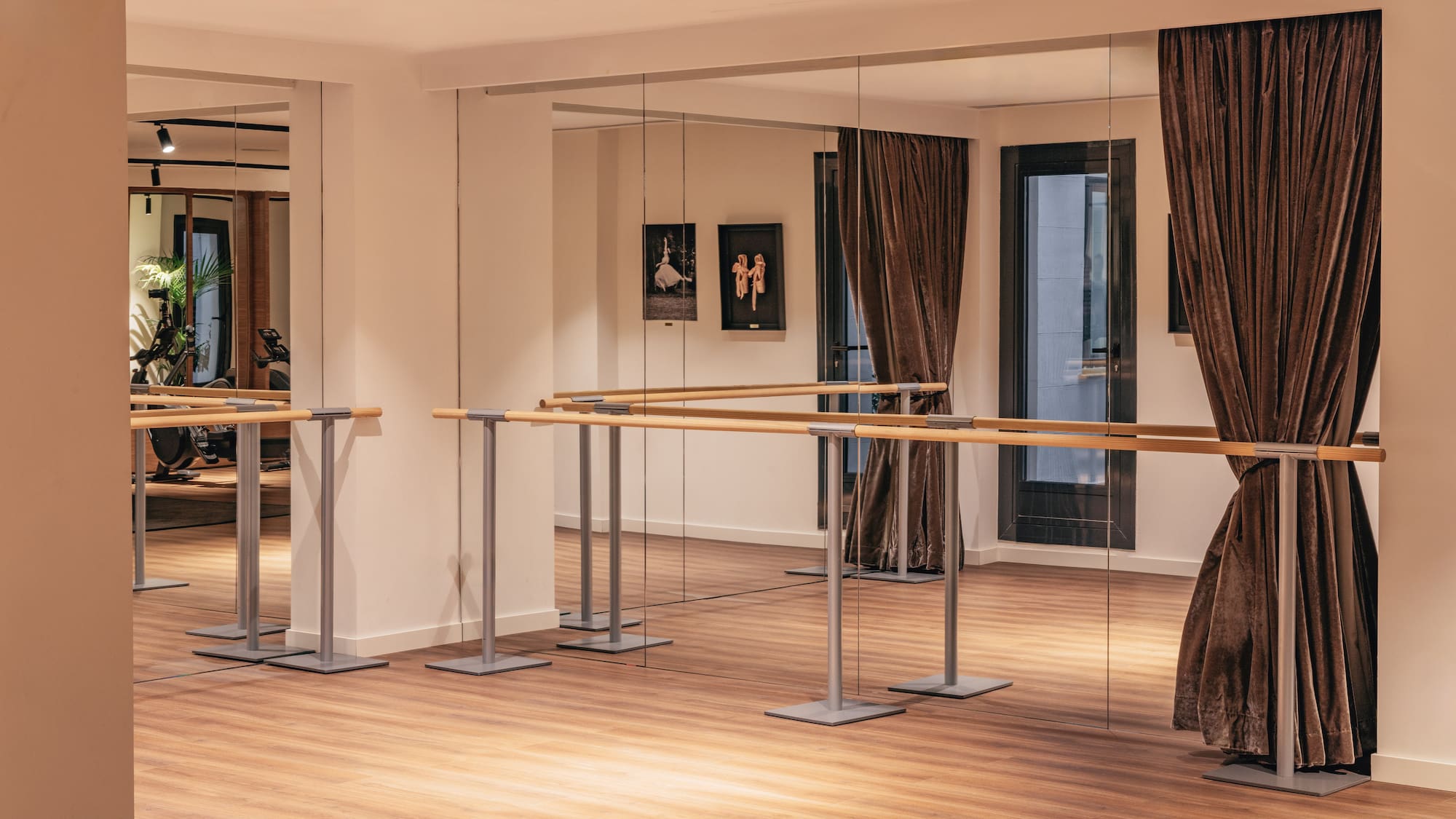 Estudio de ballet moderno con espejos, barras y suelo de madera.