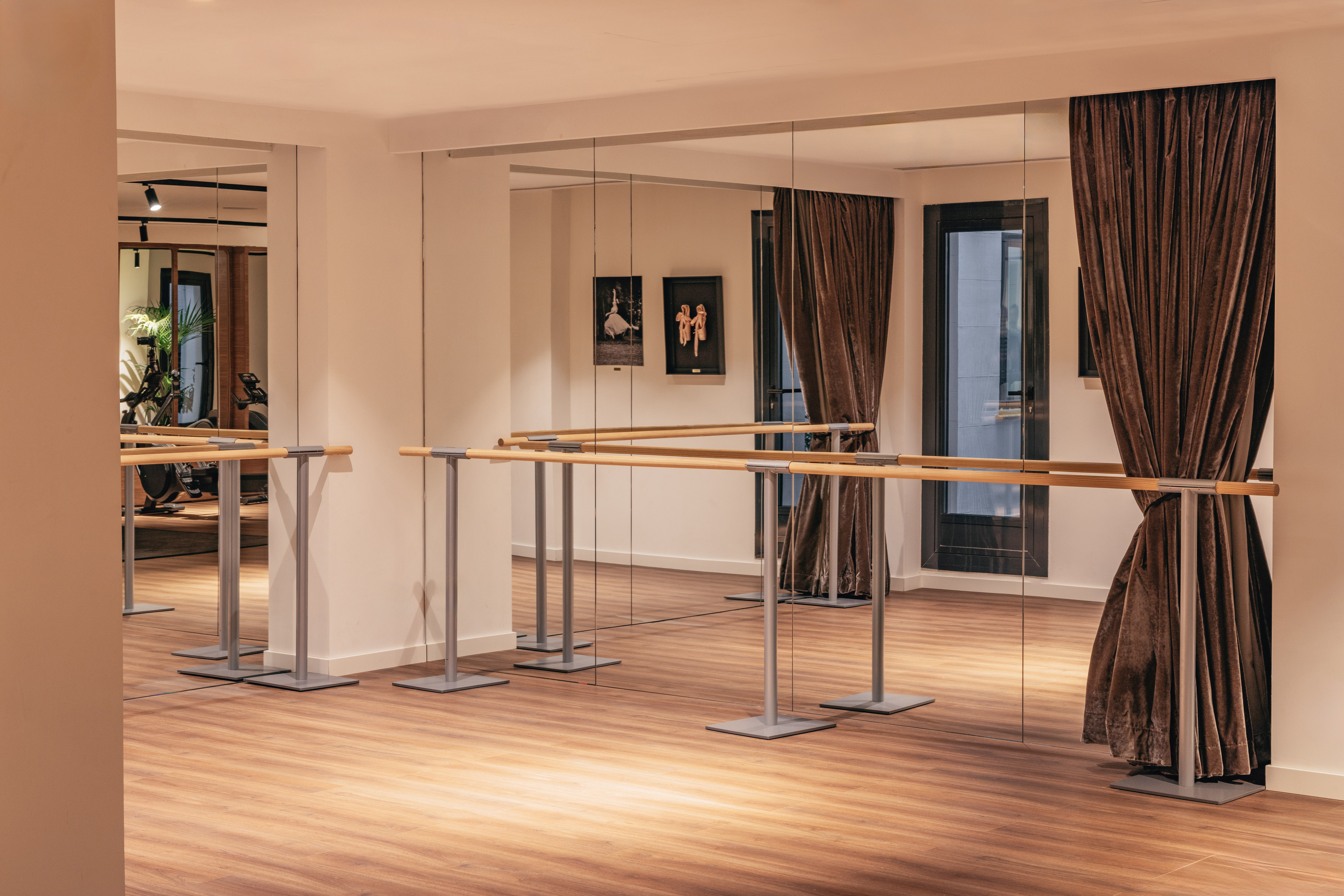 Modern dance studio with ballet barres, wall mirrors, and warm wooden floor.