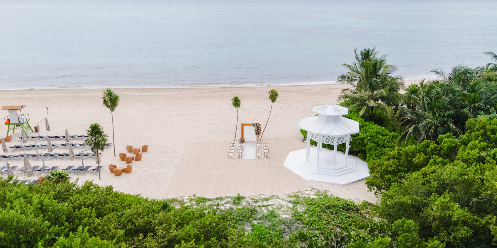 a white gazebo on a beach with palm trees