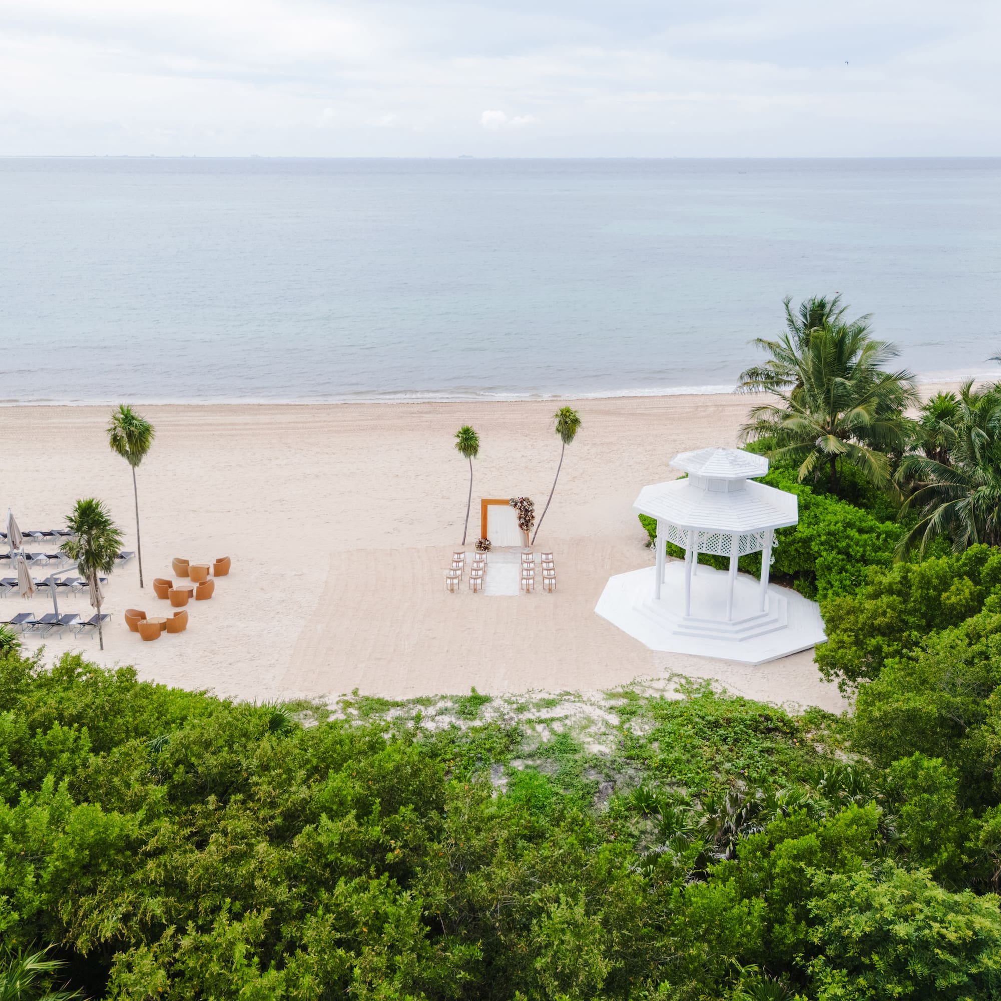 a white gazebo on a beach with palm trees