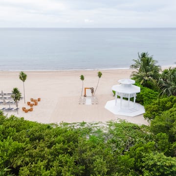 a white gazebo on a beach with palm trees