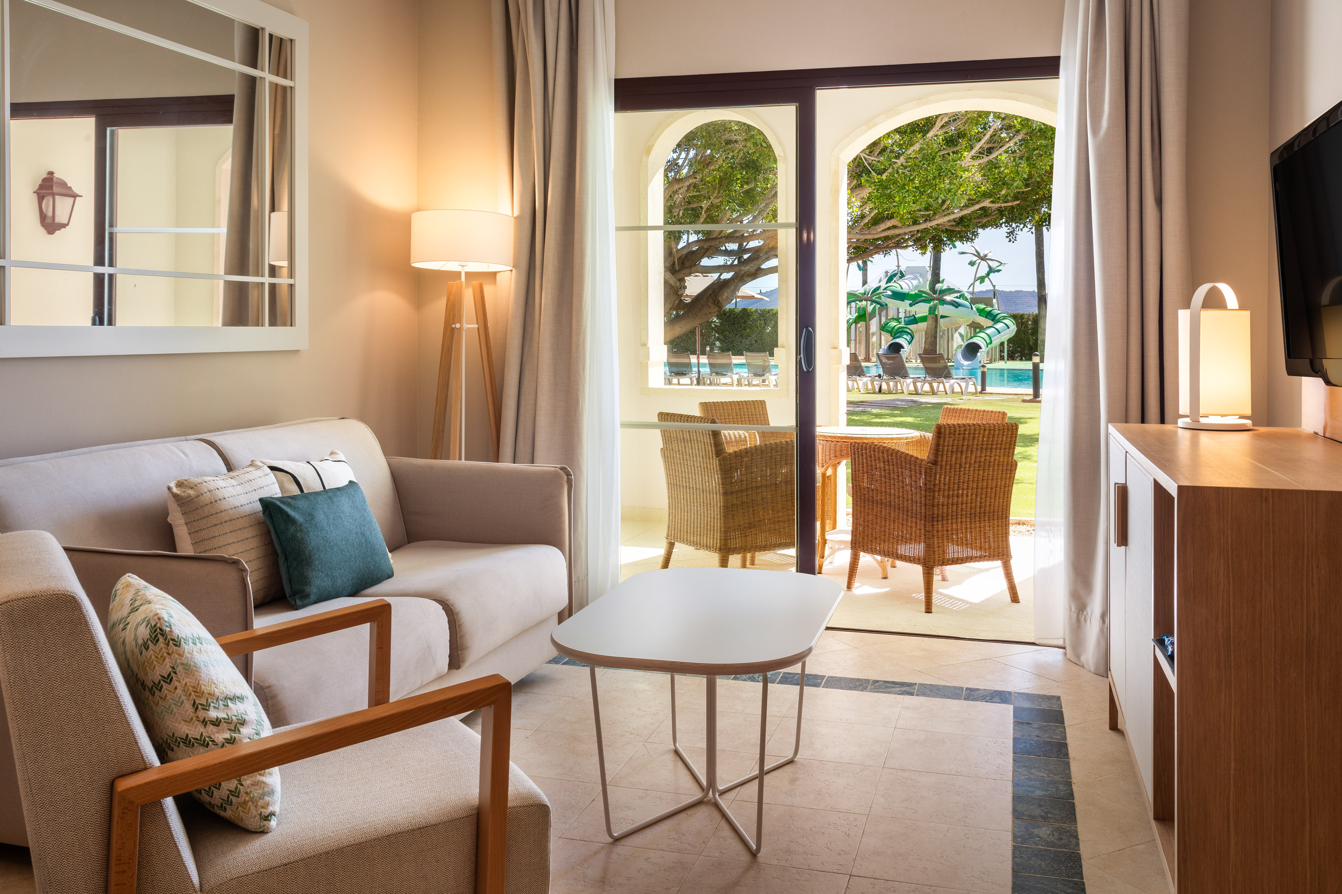Resort suite living room with patio, pool view, and waterslides.