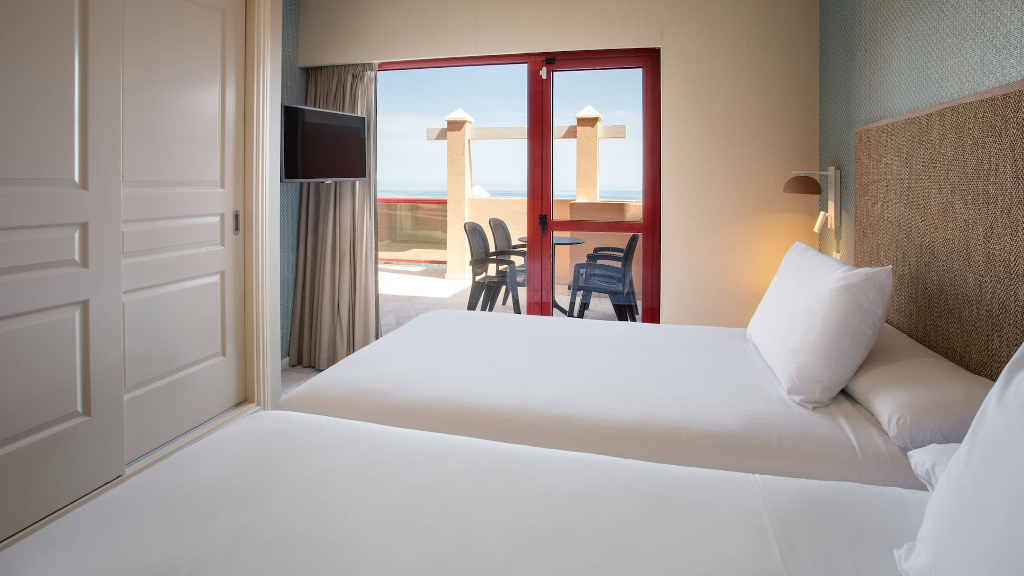 Twin hotel room with balcony overlooking the ocean.