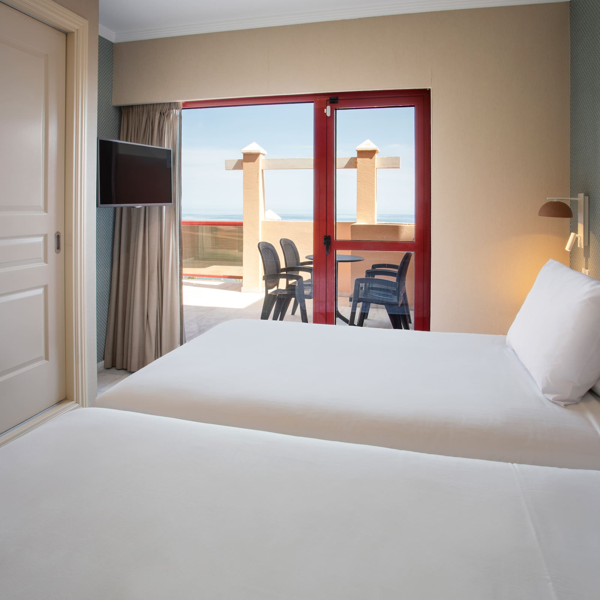 Twin hotel room with balcony overlooking the ocean.