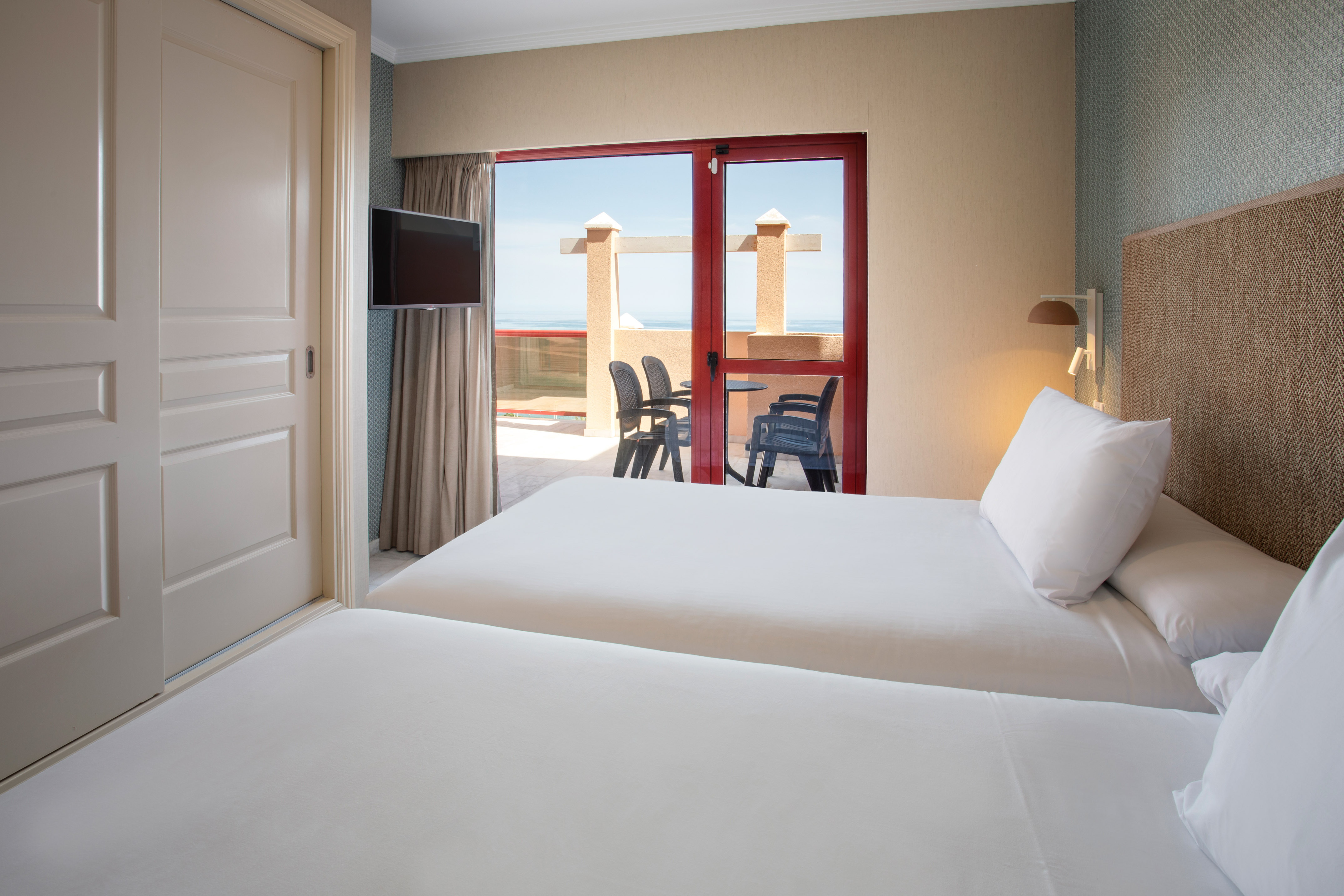 Twin hotel room with balcony overlooking the ocean.