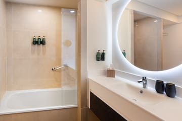 a bathroom with a round mirror and a tub