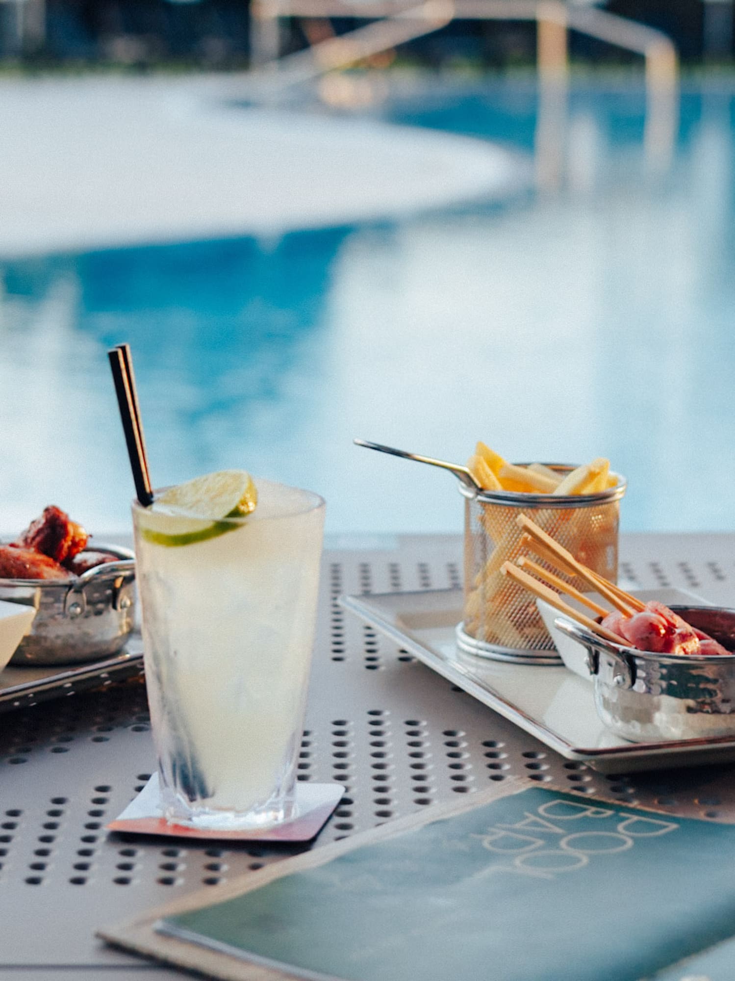 Enjoying cocktails, french fries, and appetizers by a resort swimming pool.