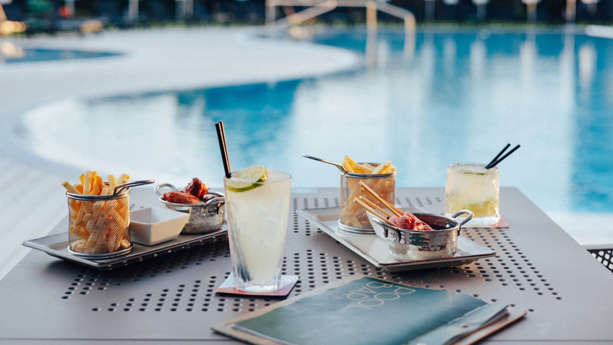 Resort poolside bar with cocktails, french fries, and snacks.