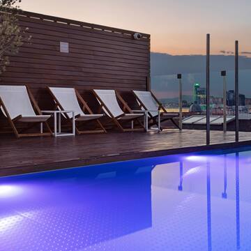 a pool with chairs and a tree in the background