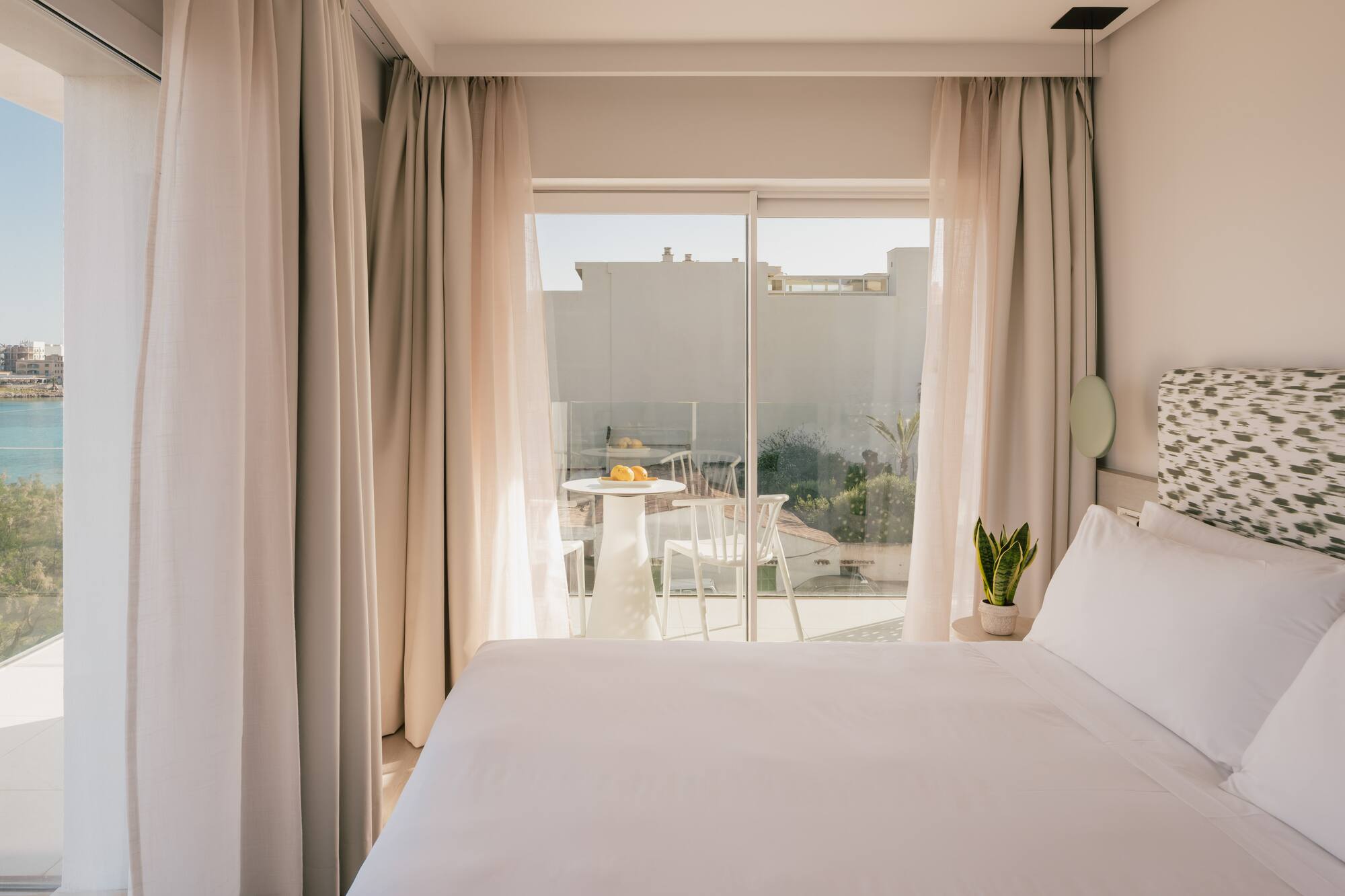 Dormitorio luminoso con cama, balcón y vista al mar.