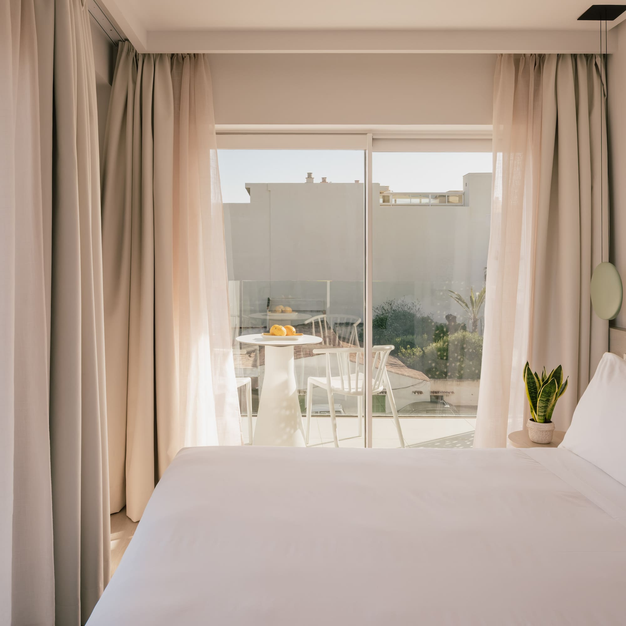 Modern hotel room with white bed, private balcony, and sea view.
