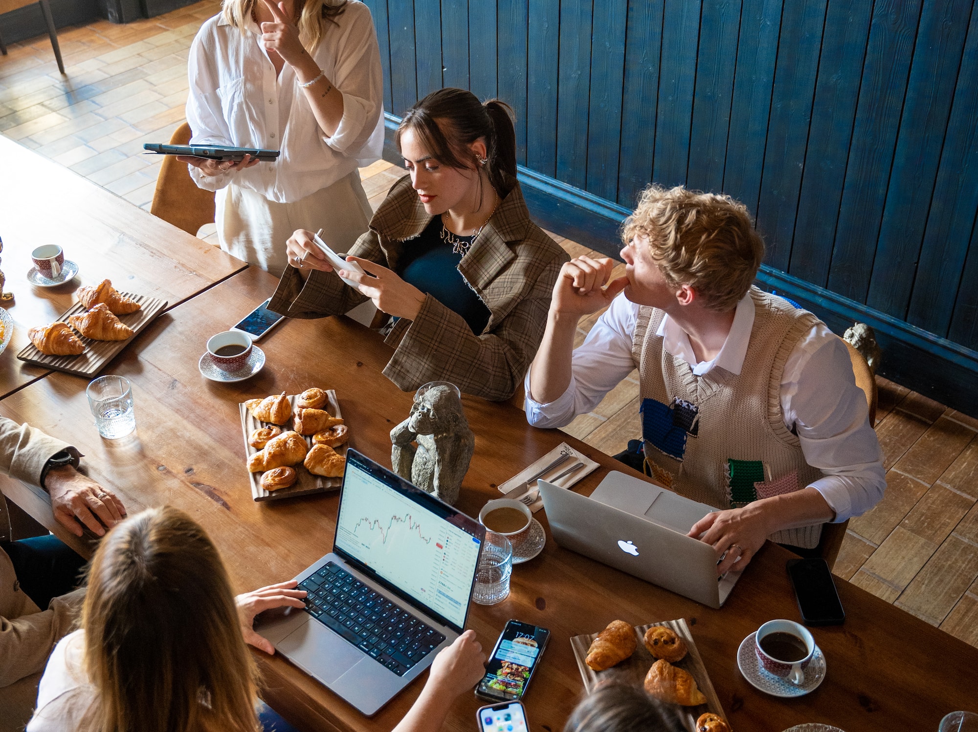 a group of people around a table with laptops and food