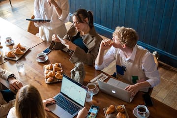 a group of people around a table with laptops and food