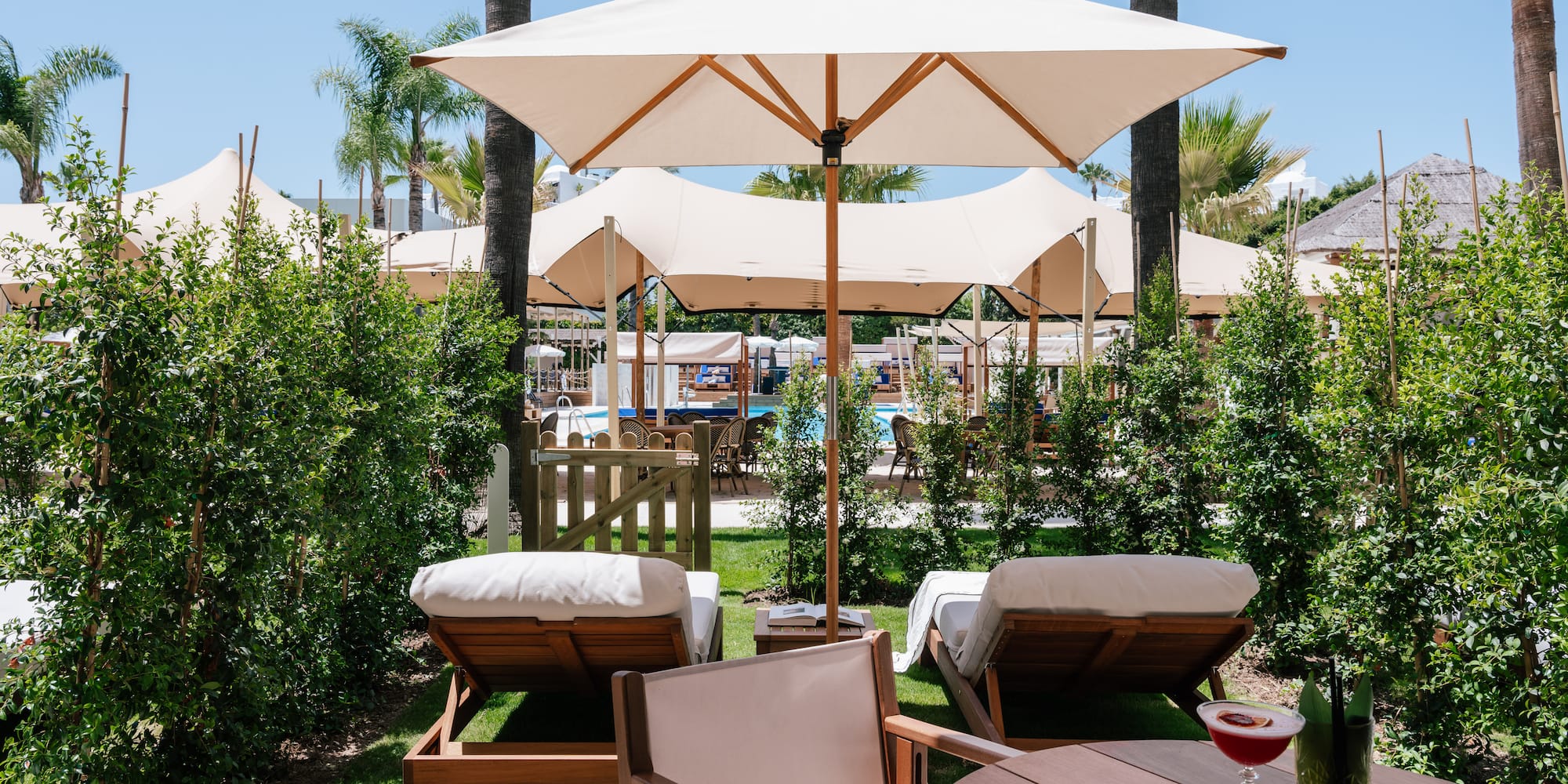 a table and chairs with umbrellas and bushes