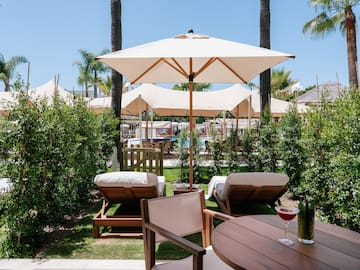 a table and chairs with umbrellas and bushes