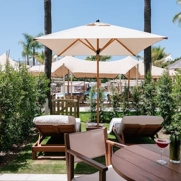 a table and chairs with umbrellas and bushes