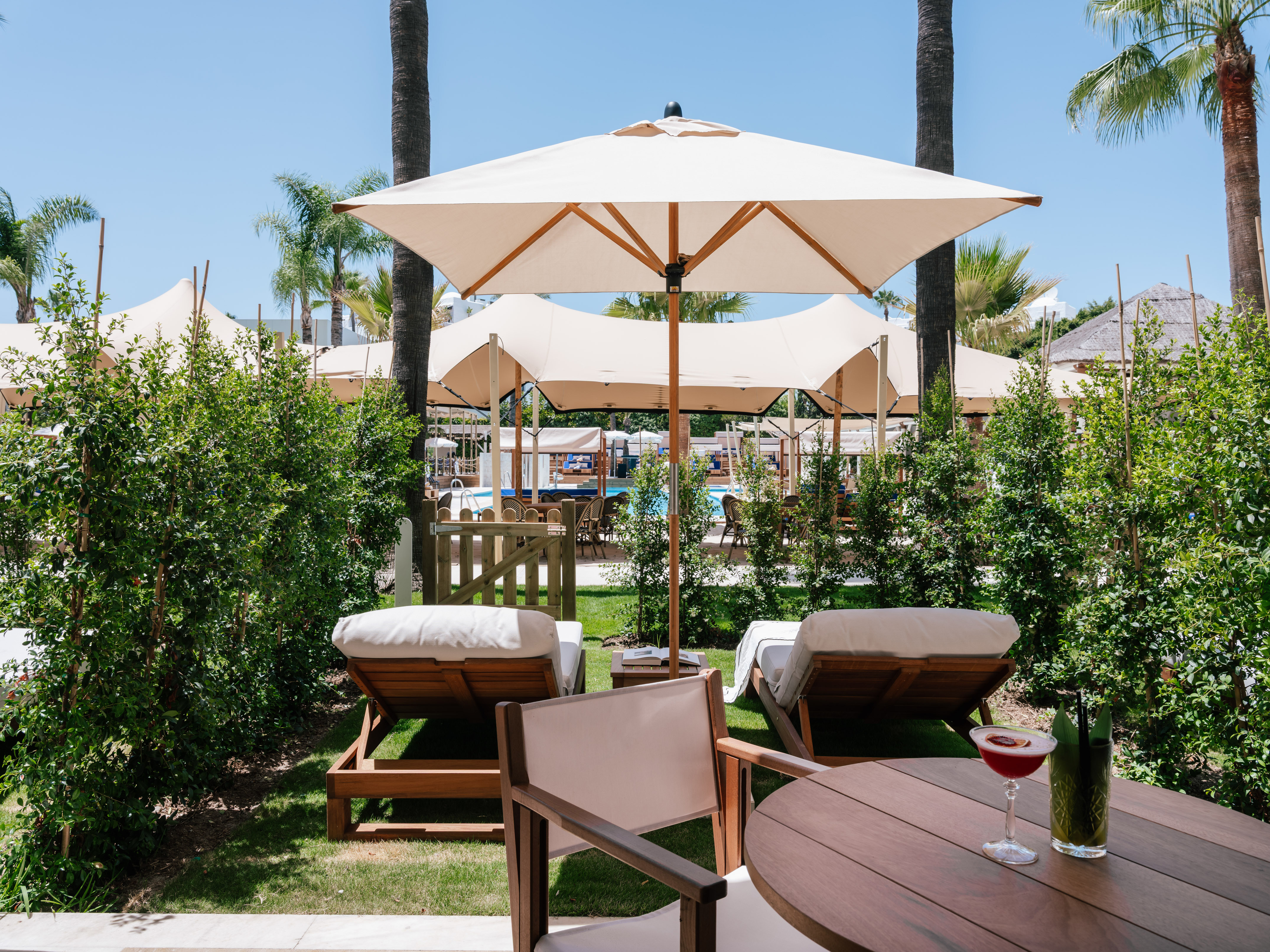 a table and chairs with umbrellas and bushes