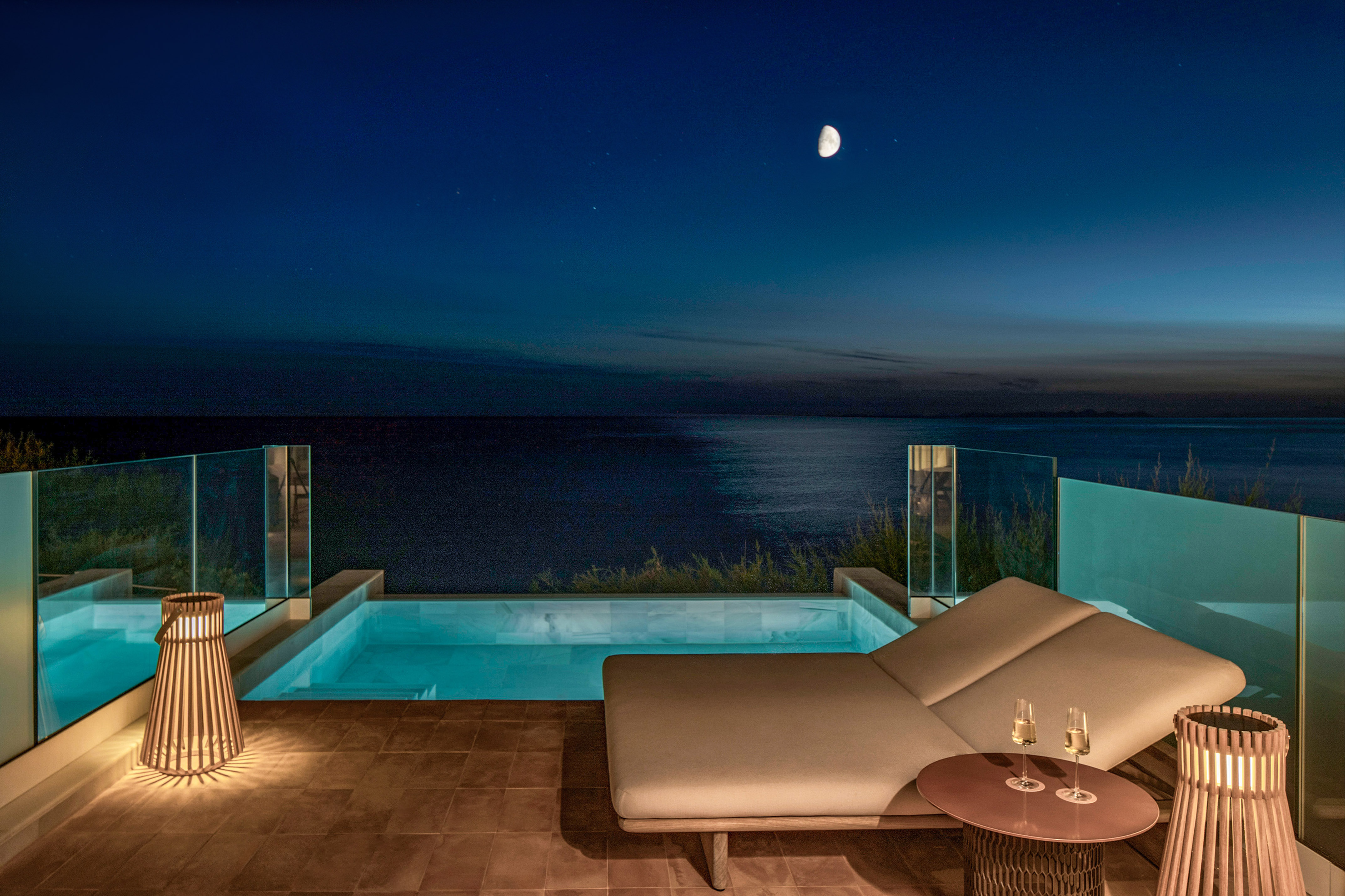 Luxury private pool balcony with ocean view at night, moon and stars.