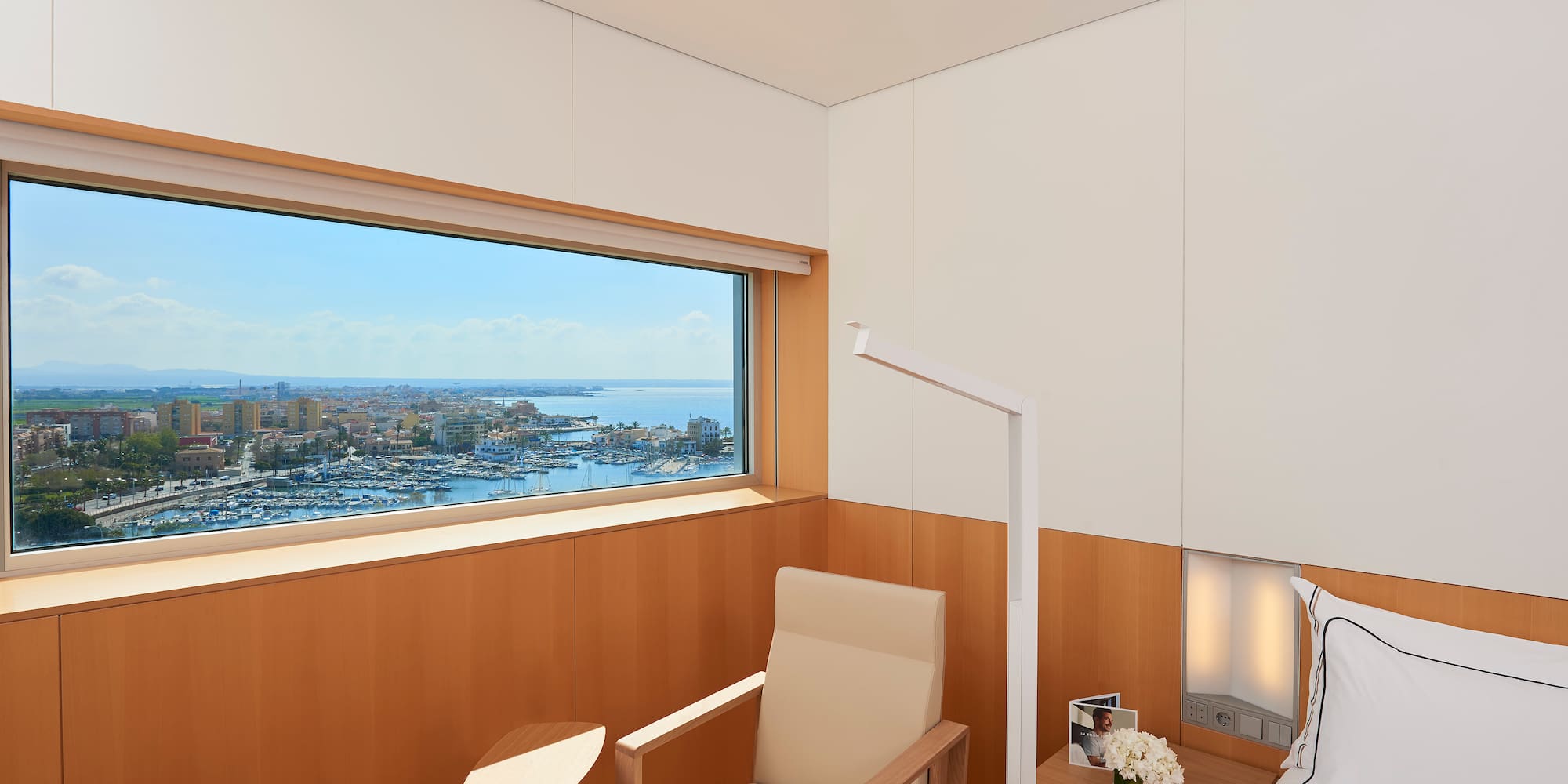 a room with a bed and a window overlooking a city