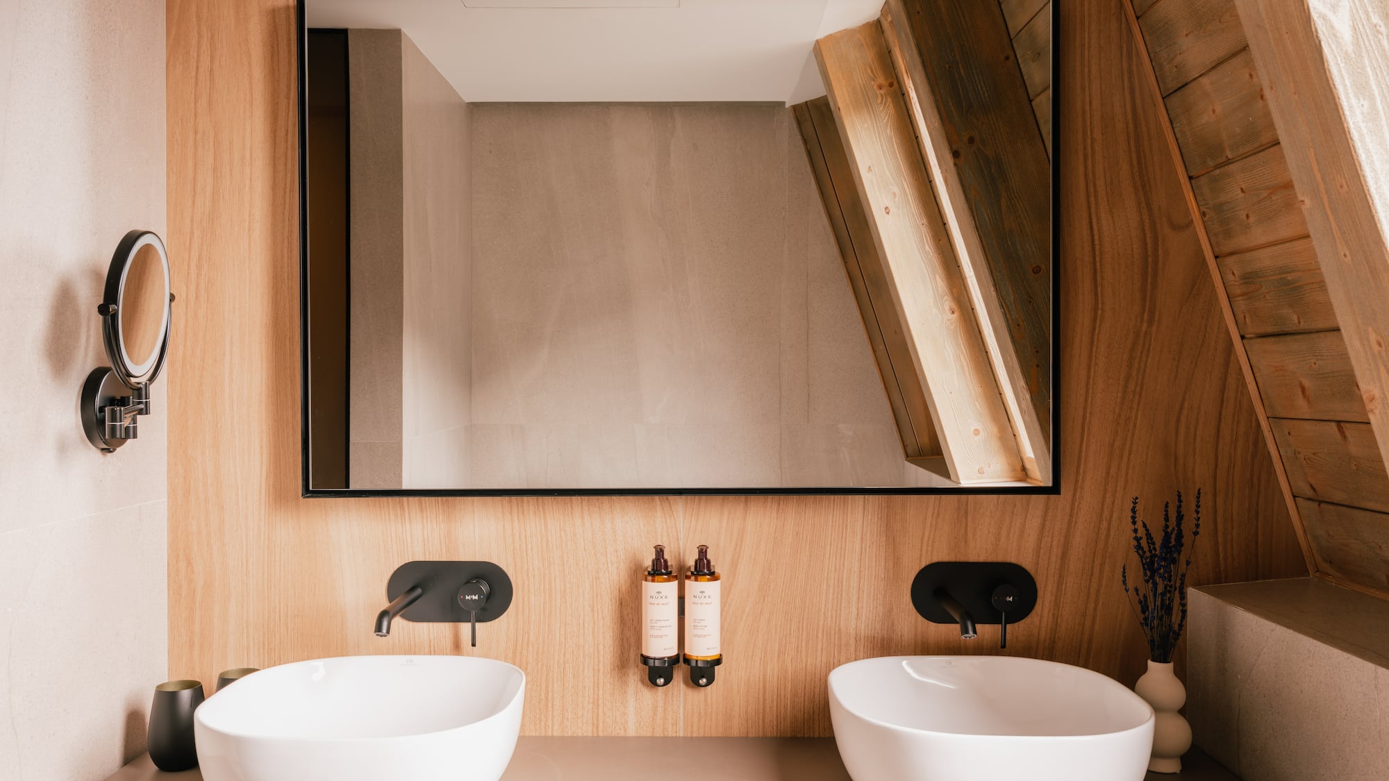 Modern wooden bathroom vanity with double sinks, black faucets, and mirror.