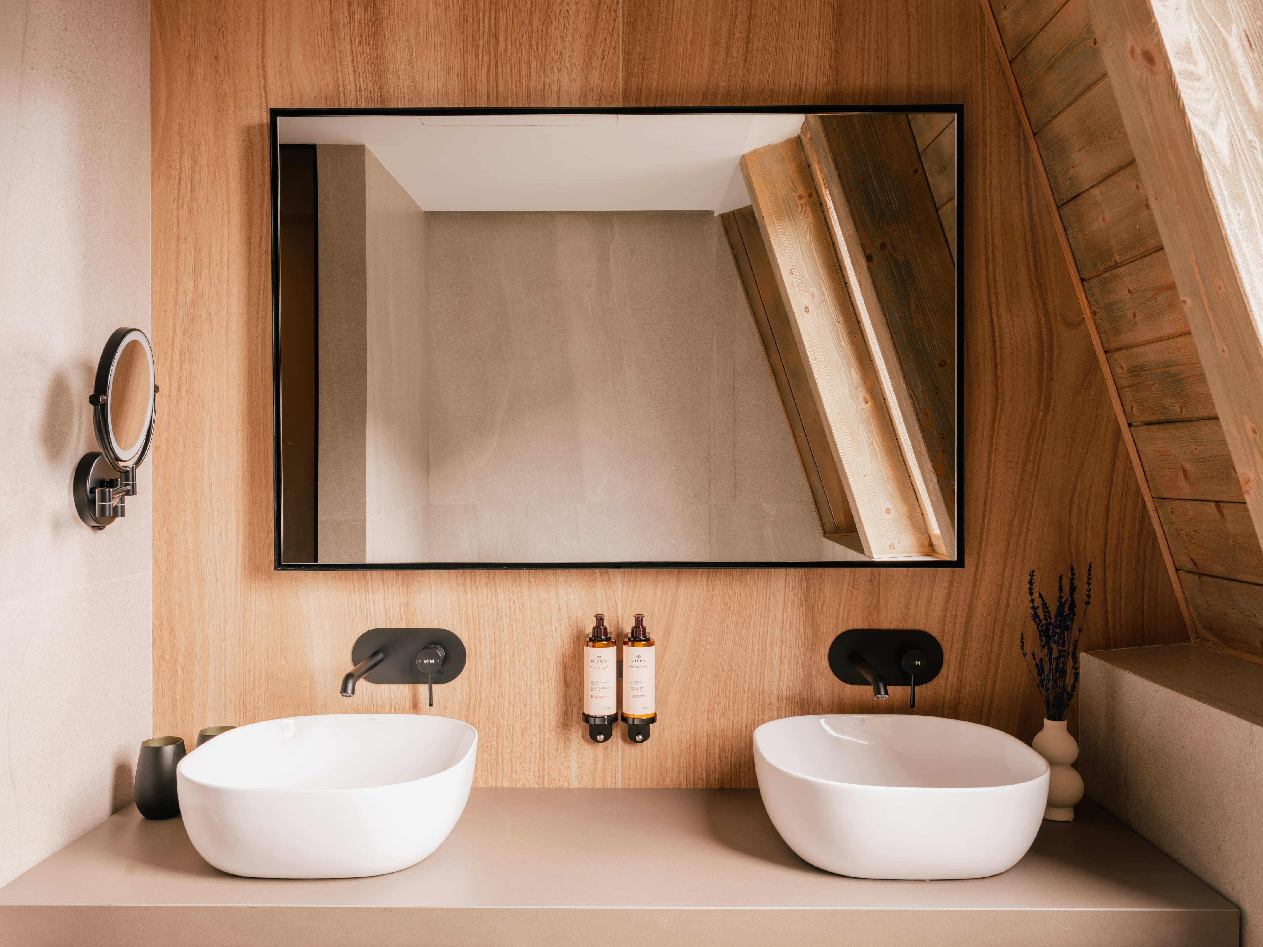 Modern wooden bathroom vanity with double sinks, black faucets, and mirror.