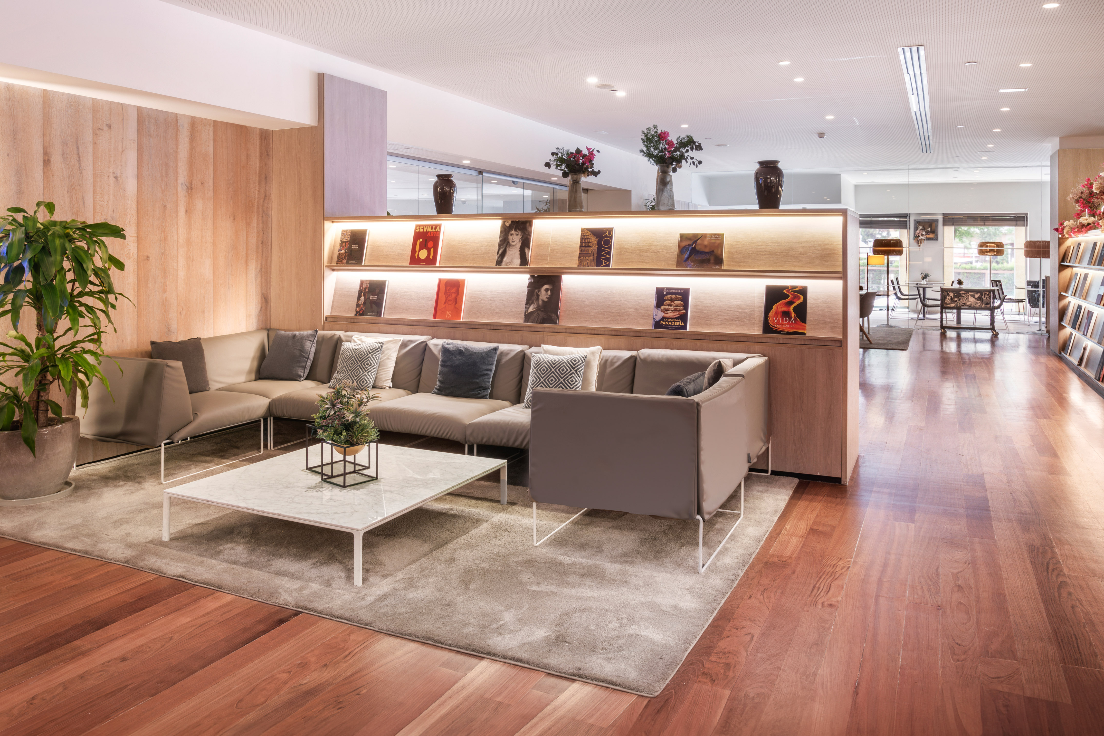 Modern lounge with comfortable sofa, wooden floors, and illuminated book display.