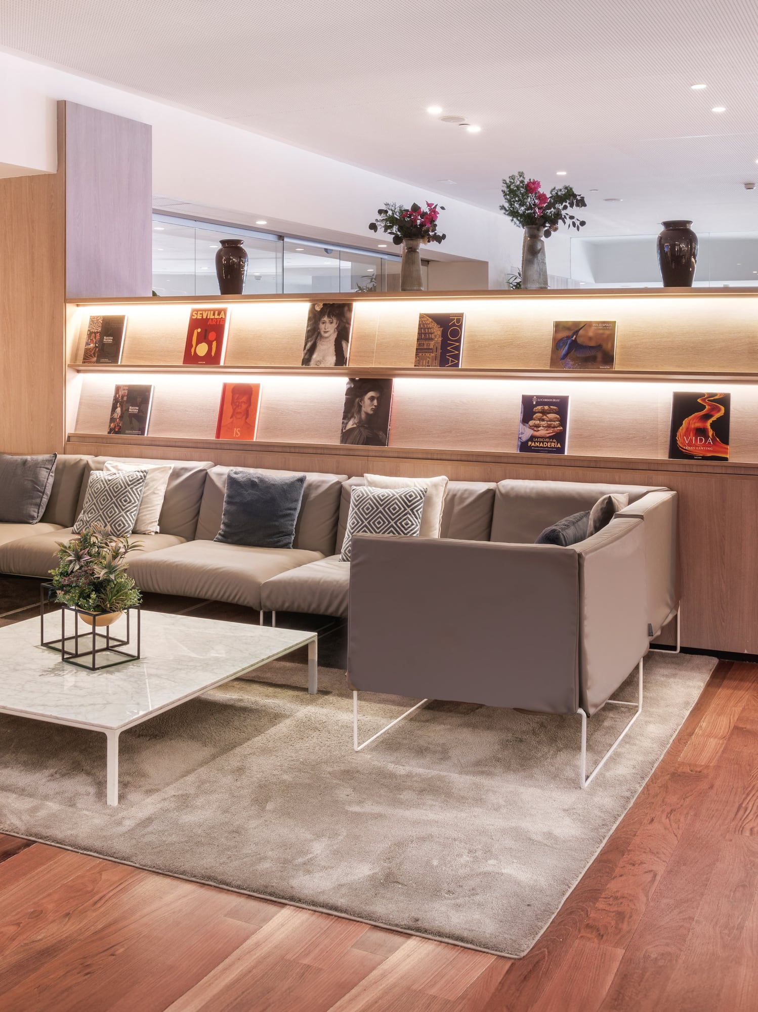 Modern lounge with comfortable sofa, wooden floors, and illuminated book display.