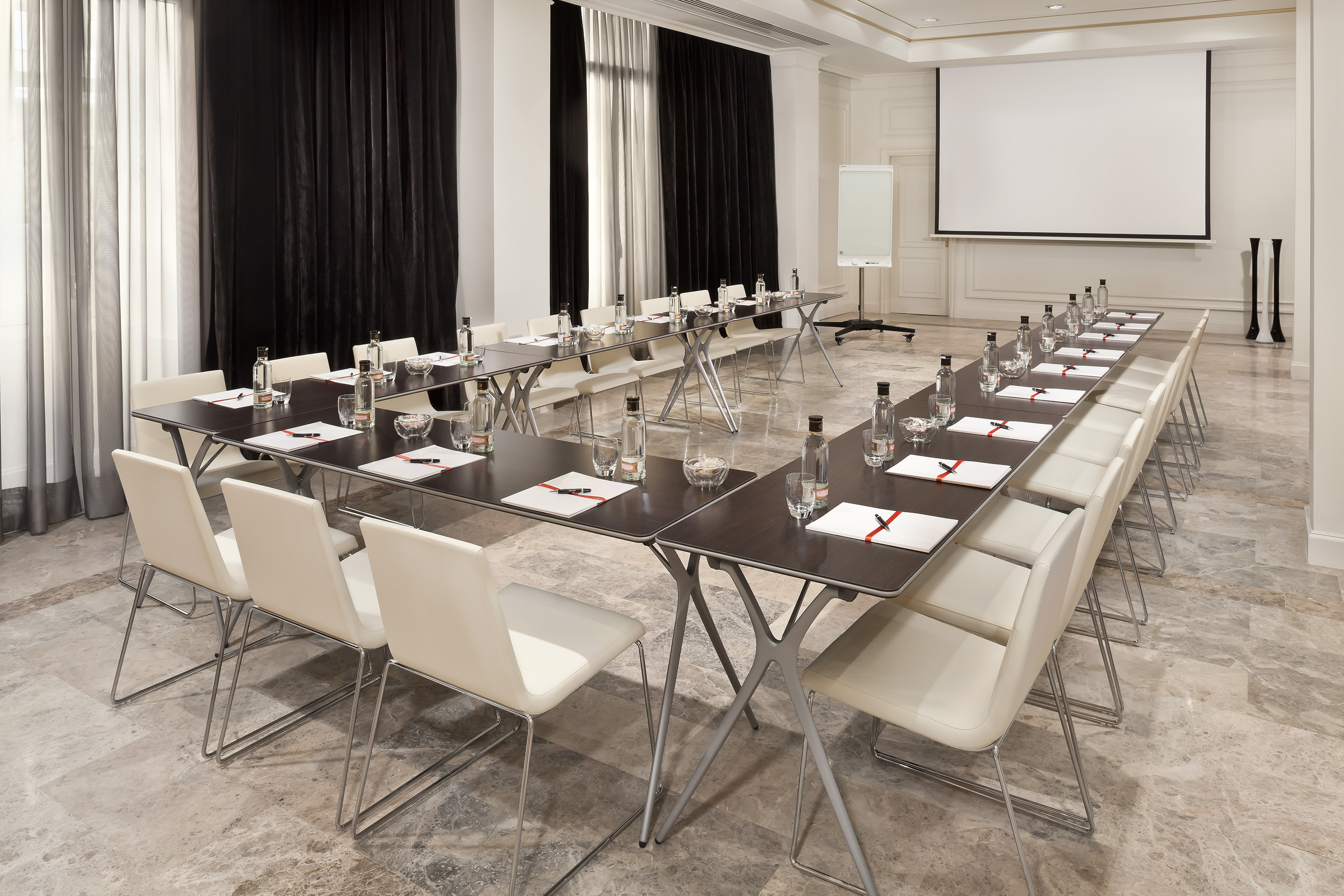 U-shape conference room setup with projection screen, whiteboard, and amenities.