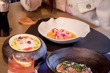 a person holding a drink and a plate of food