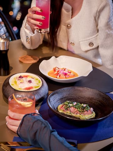 a person holding a drink and a plate of food